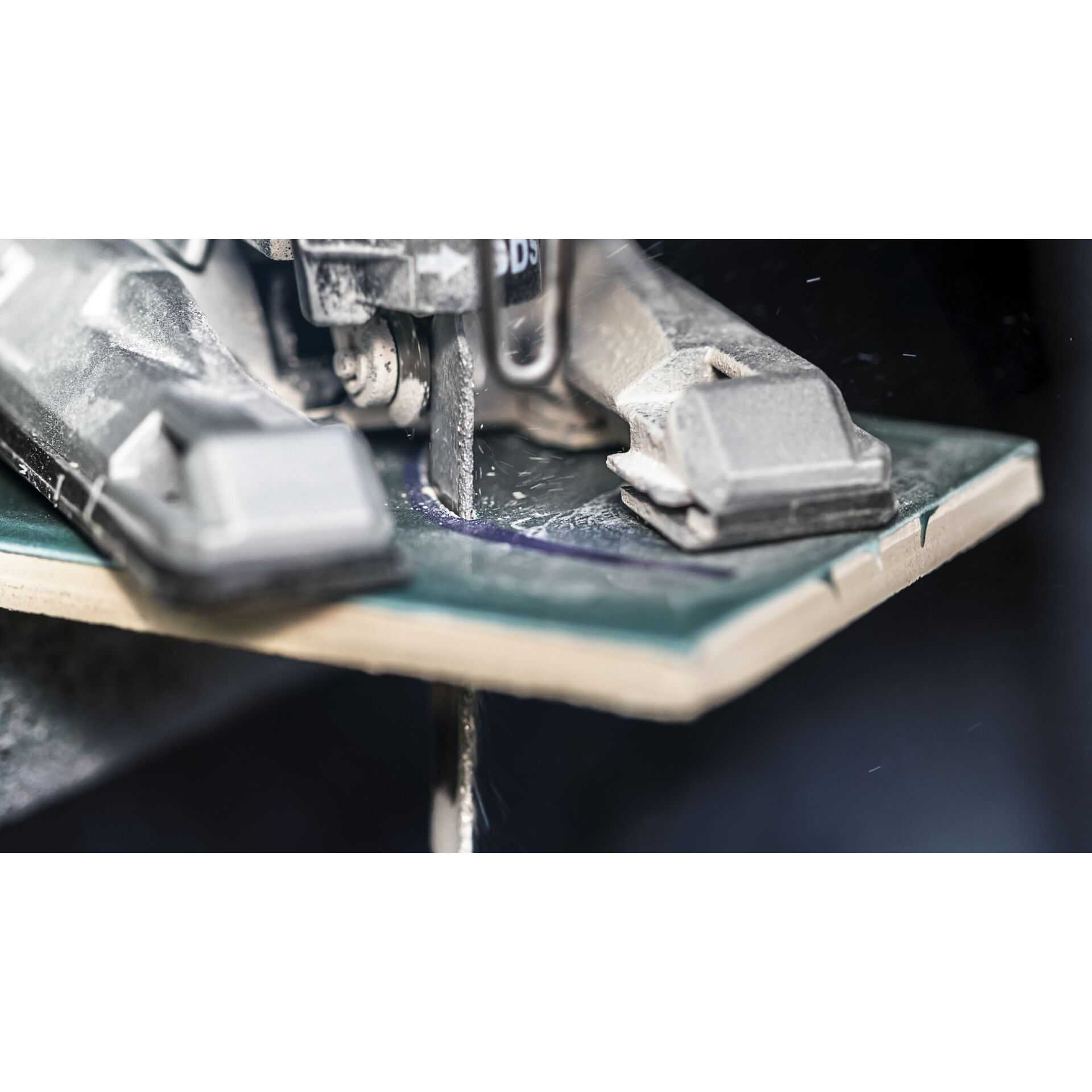 Piła tnie płytkę. Piła jest srebrna, a płytka zielona. Iskry lecą.