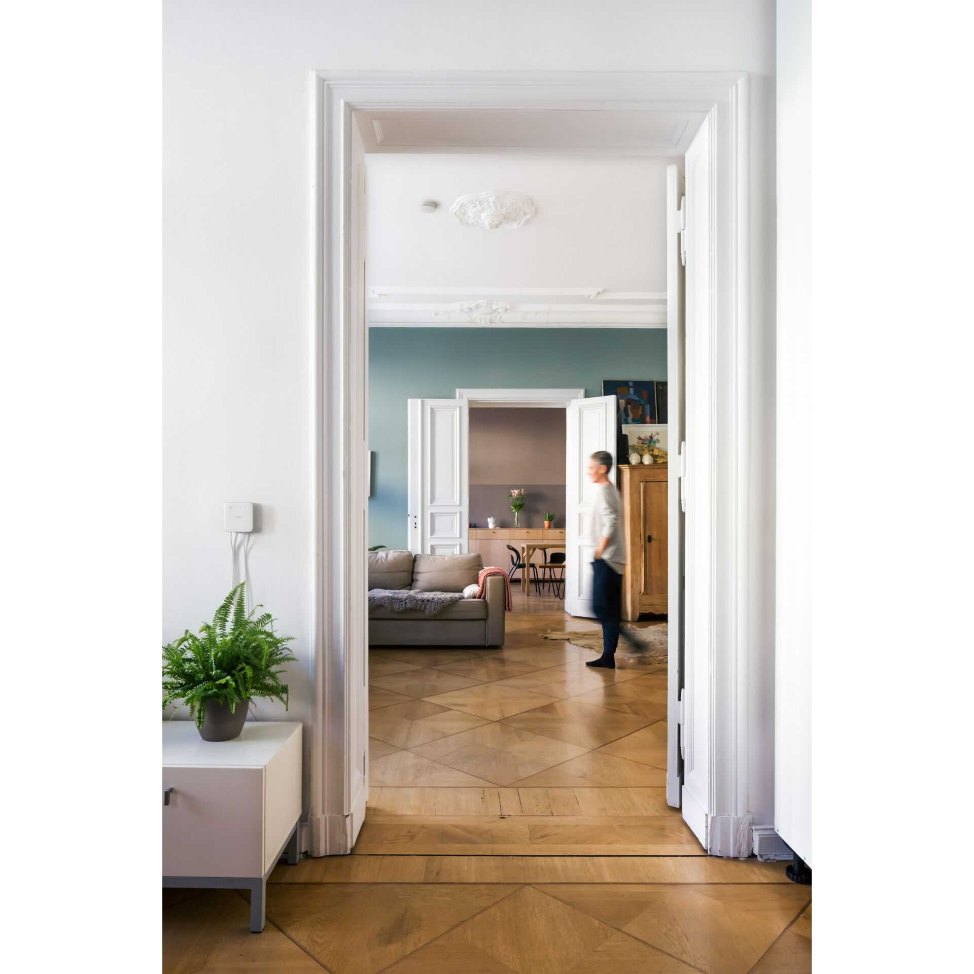 Widok wnętrza pokoju z mężczyzną przechodzącym przez drzwi.