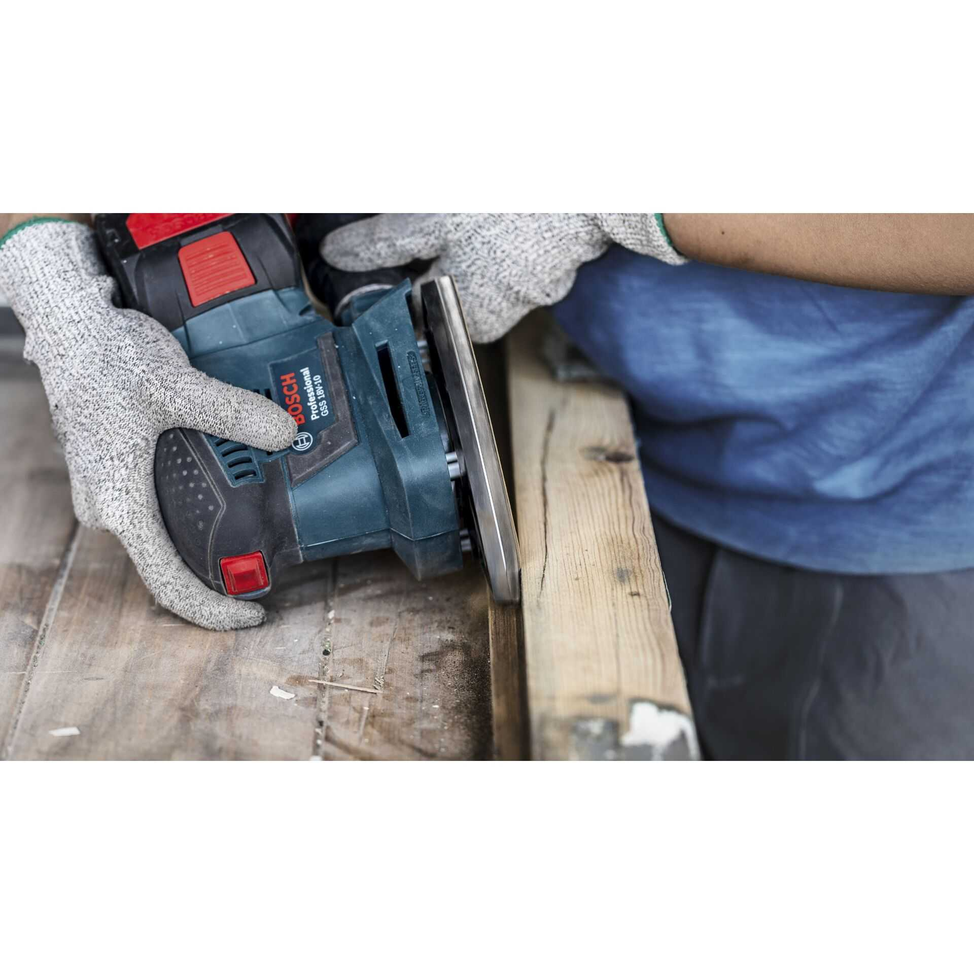 Person schleift Holz mit einem Schleifer, trägt Handschuhe.