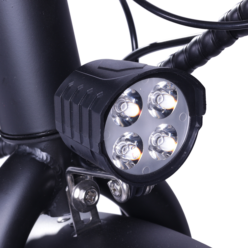 Zbliżenie czarnego reflektora rowerowego z czterema jasnymi diodami LED, zamontowanego na ramie.