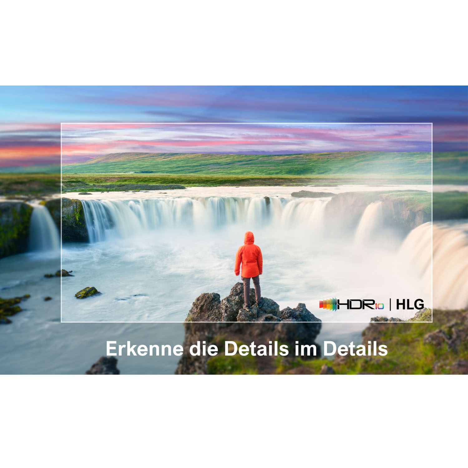 Eine Person in roter Jacke steht vor einem Wasserfall.
