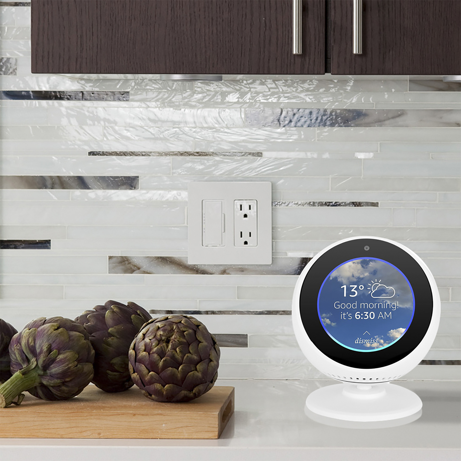 Pantalla inteligente mostrando el clima. Alcachofas en tabla de cortar. Encimera de cocina.