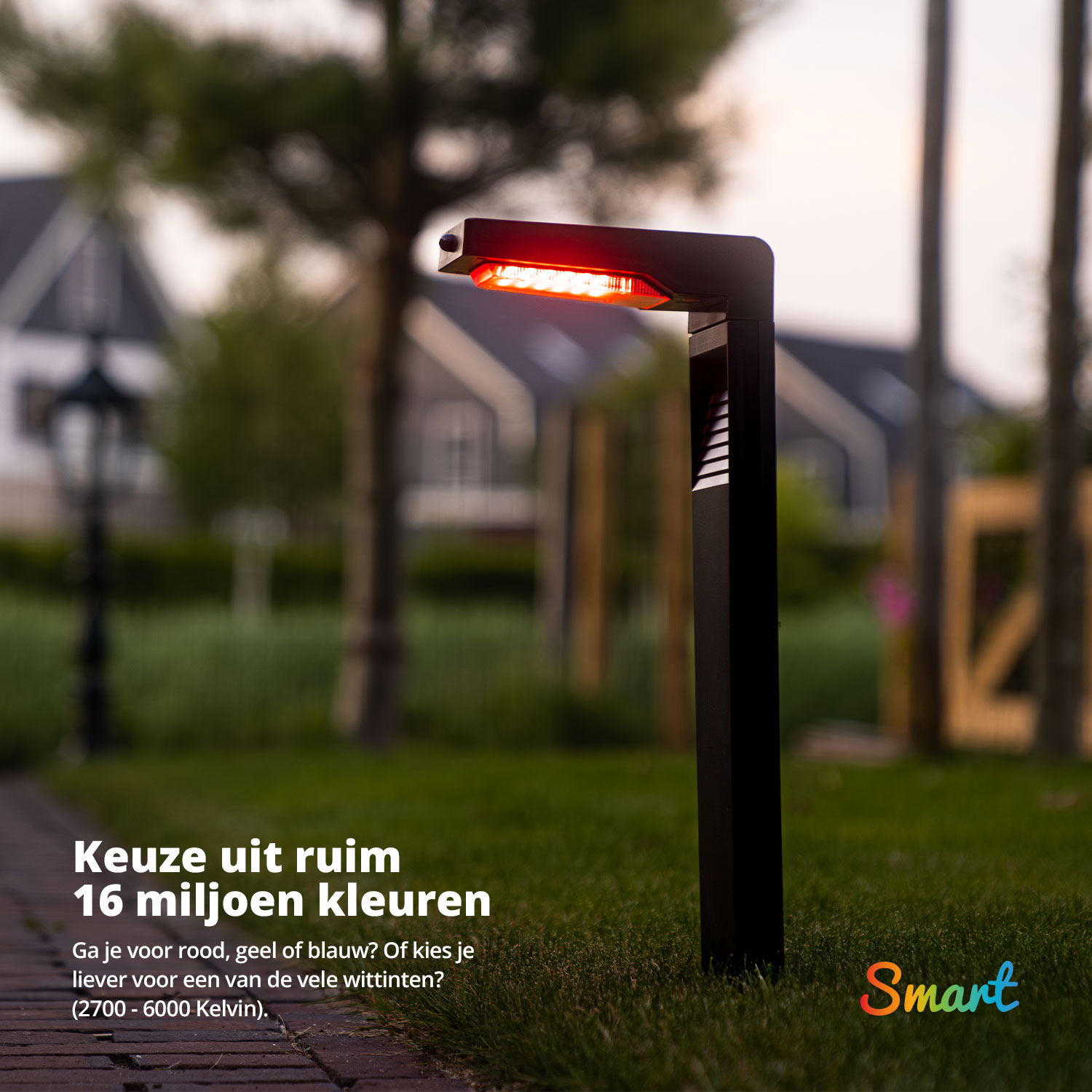 Zwarte buitenlamp die rood licht uitstraalt op een pad met bomen en huizen op de achtergrond.
