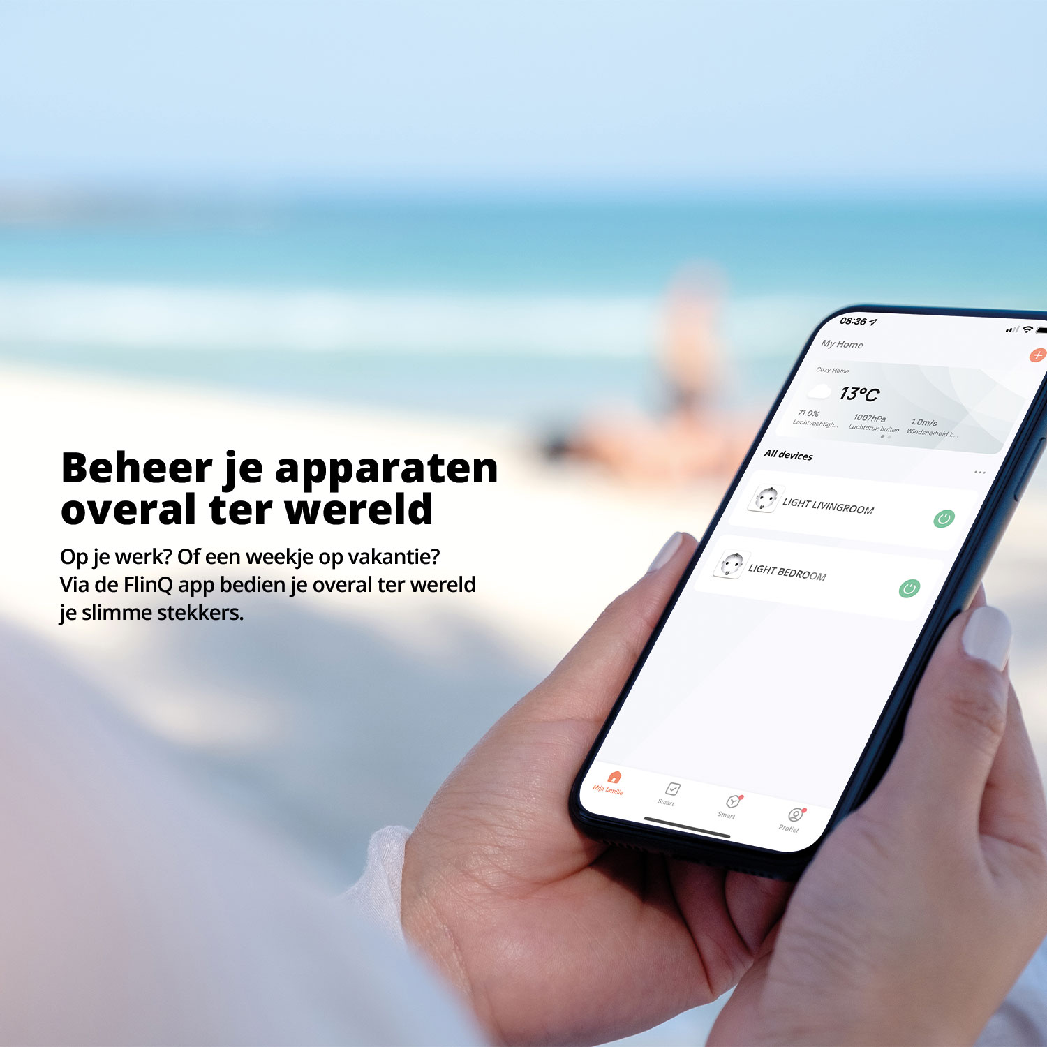 A person holding a smartphone displaying a smart home app on a beach with the ocean in the background.