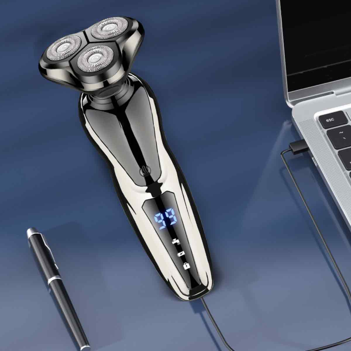Elektrorasierer neben Laptop und Stift auf blauer Oberfläche, an ein Ladegerät angeschlossen.