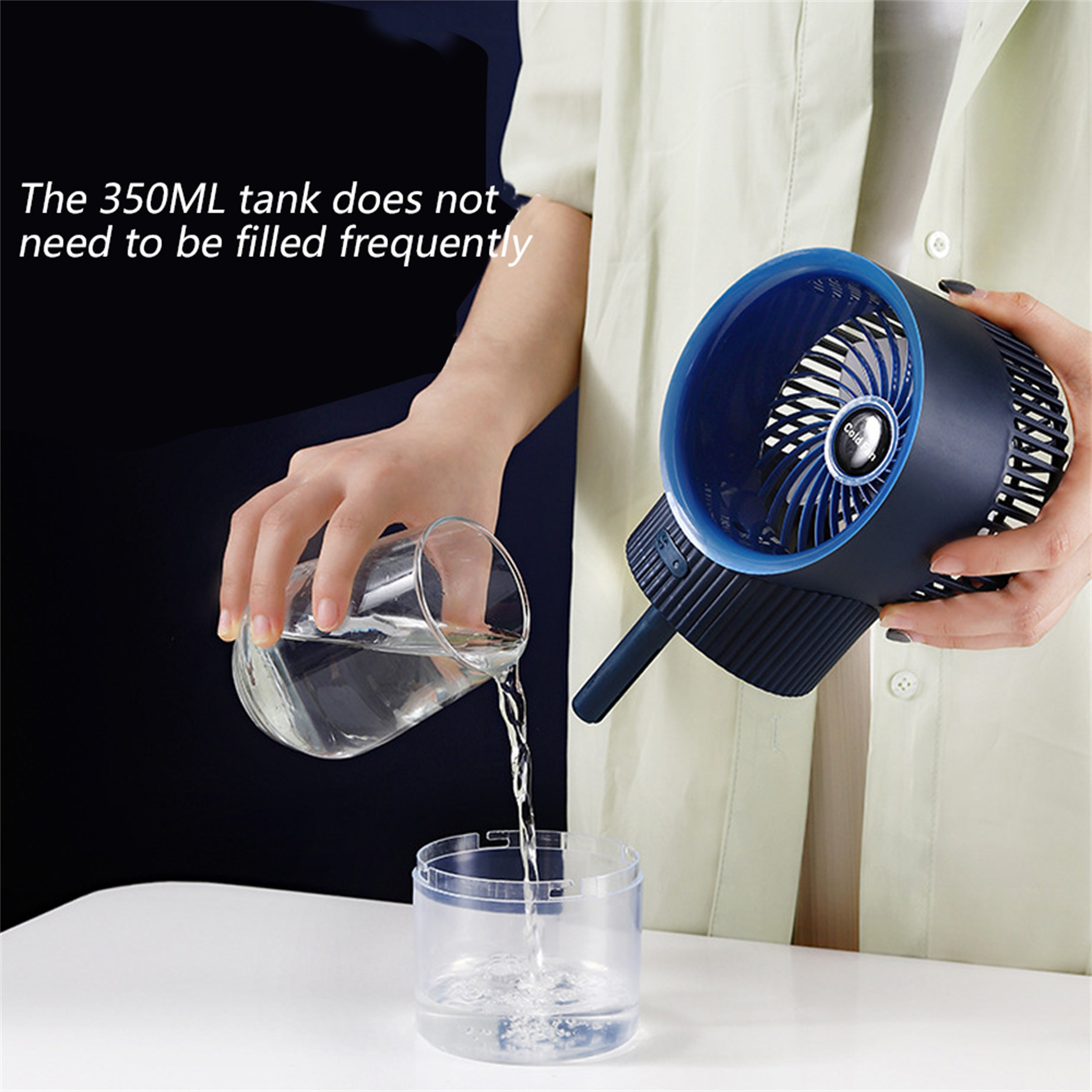 Eine Person gießt Wasser in einen transparenten Behälter neben einem dunkelblau-weißen Ventilator.