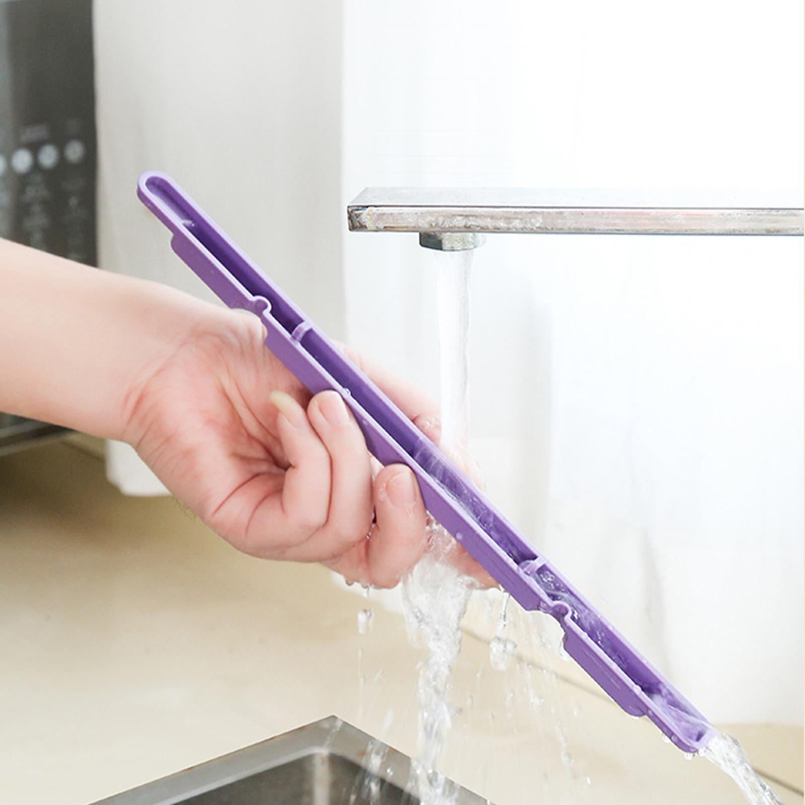 Hand hält lila Kunststoffwerkzeug unter fließendem Wasser aus einem Wasserhahn.