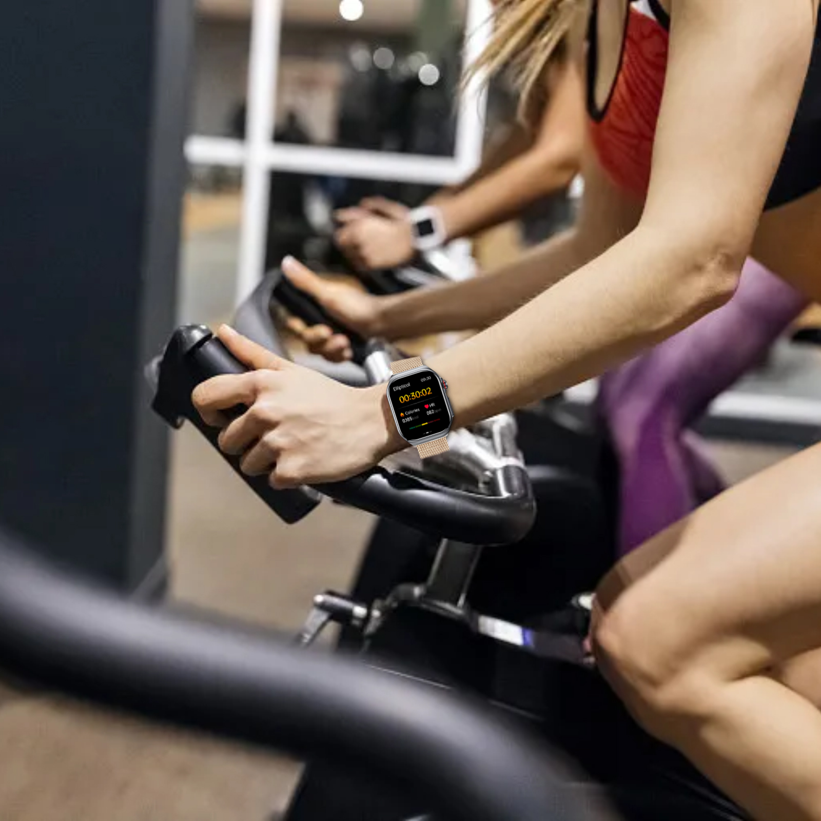 Frau auf dem Heimtrainer, trägt eine Smartwatch mit Trainingsdaten auf dem Bildschirm.