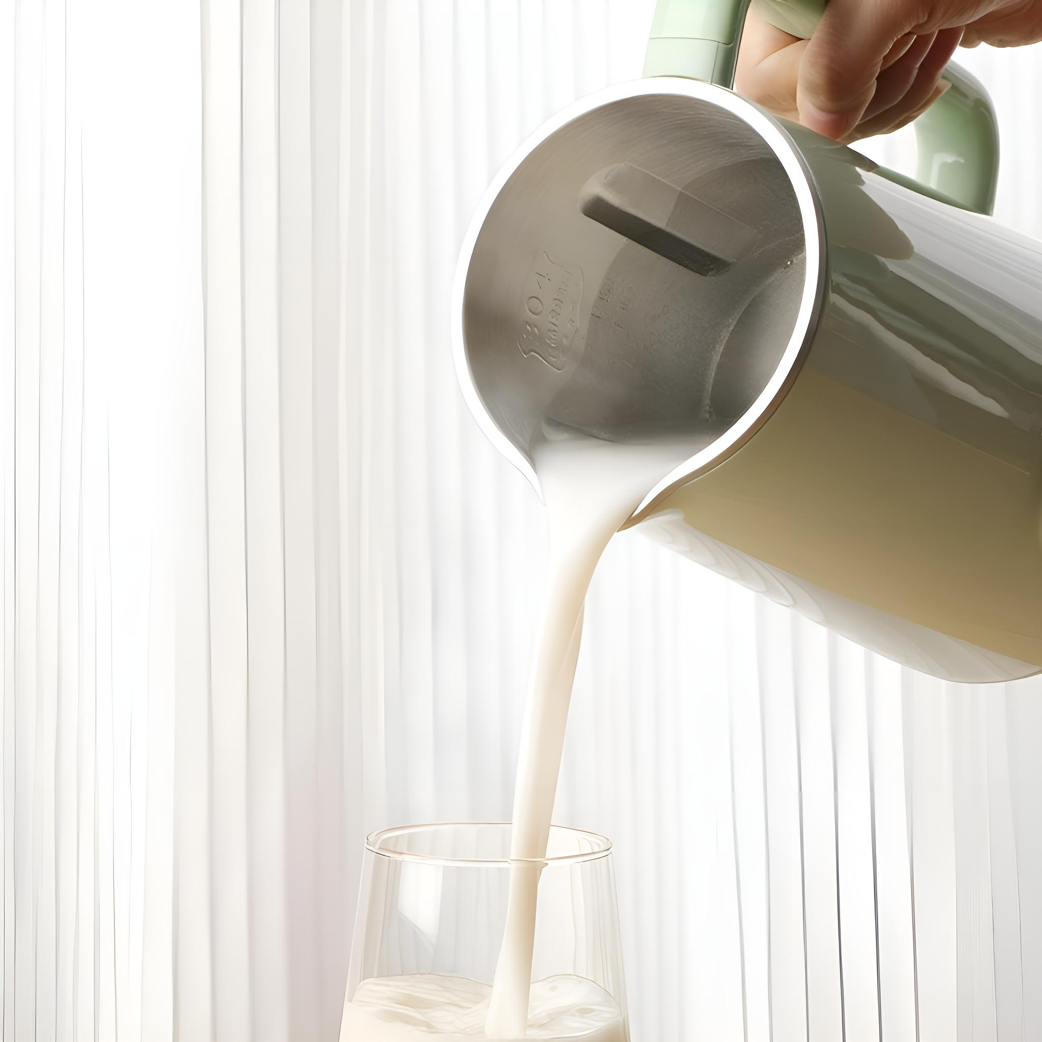 Milch wird aus einem grünen elektrischen Wasserkocher in ein klares Glas gegossen.