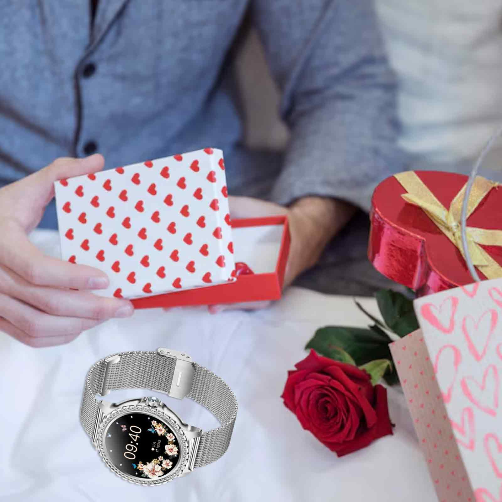 Eine Person hält eine Geschenkbox und eine Rose, mit einer Smartwatch am Handgelenk und einer Einkaufstasche mit Herzmuster.