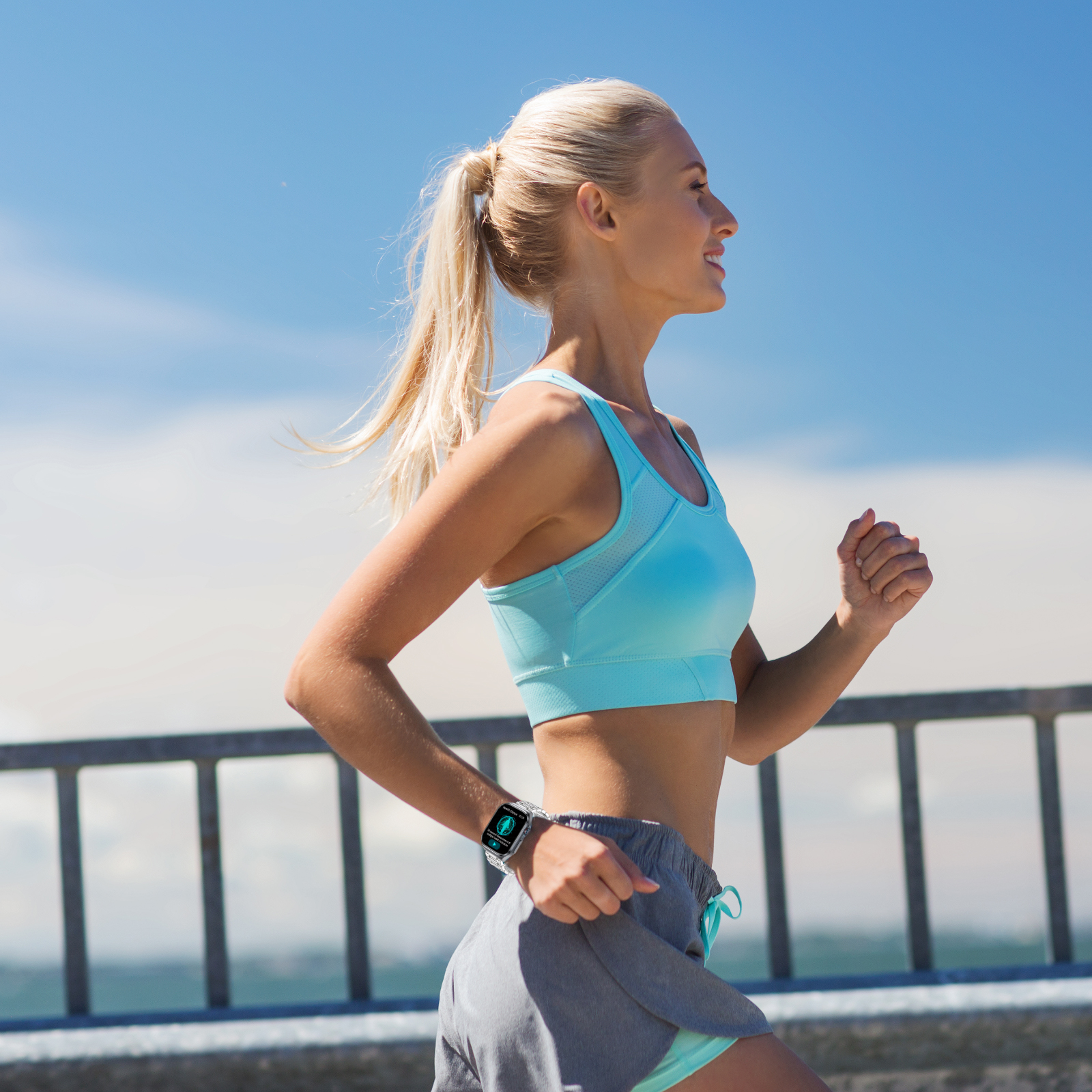 Frau läuft draußen und trägt eine Smartwatch, blaues Oberteil und graue Shorts.