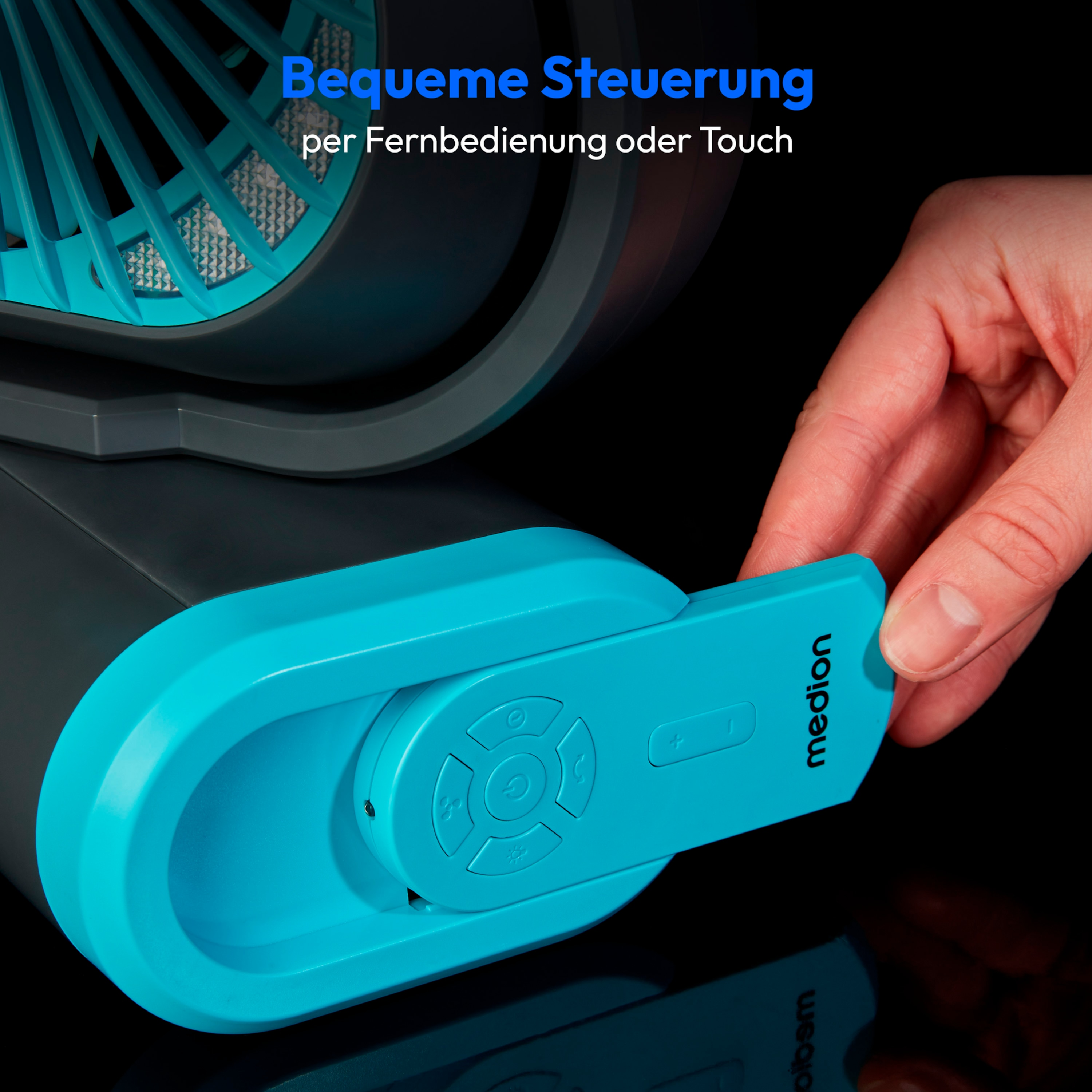 A hand holding the remote control of a turquoise and grey fan, buttons are visible.