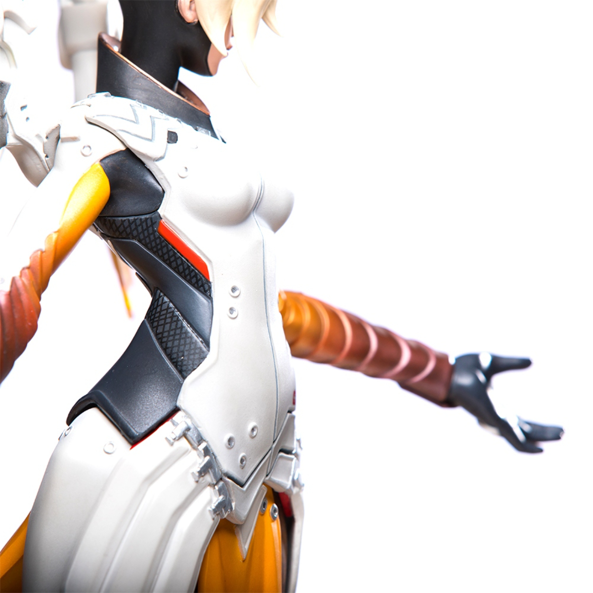 Nahaufnahme der Mercy-Statue: weiße Uniform, orangefarbene Akzente, schwarze Akzente und ein Roboterarm.