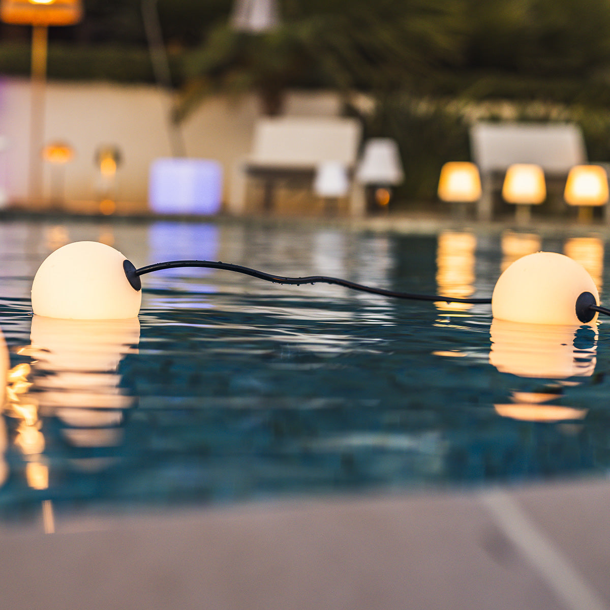 Lichter in einem Pool. Die Lichter sind weiße Kugeln. Der Hintergrund ist ein Pool und Lampen.