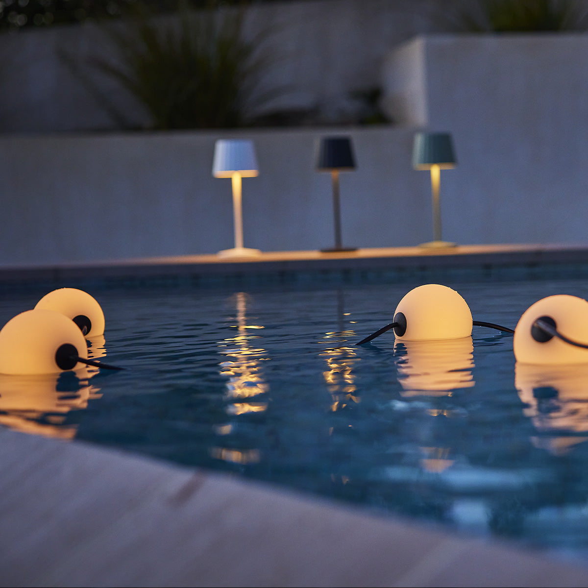 Pool mit schwimmenden Lichtern. Drei Lampen im Hintergrund.