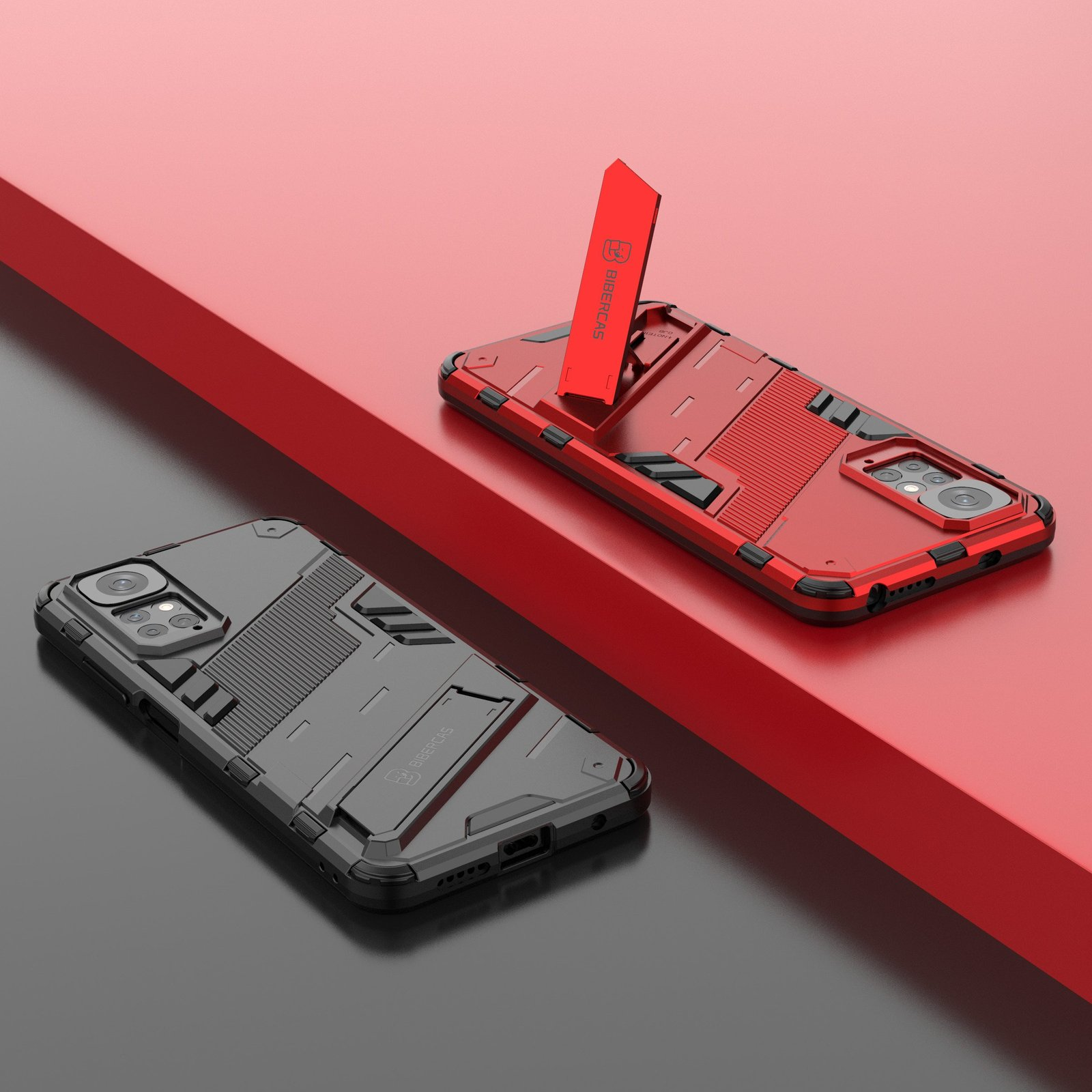 Dos fundas para teléfono, una roja con soporte y otra gris. Ambas sobre una superficie roja y negra.