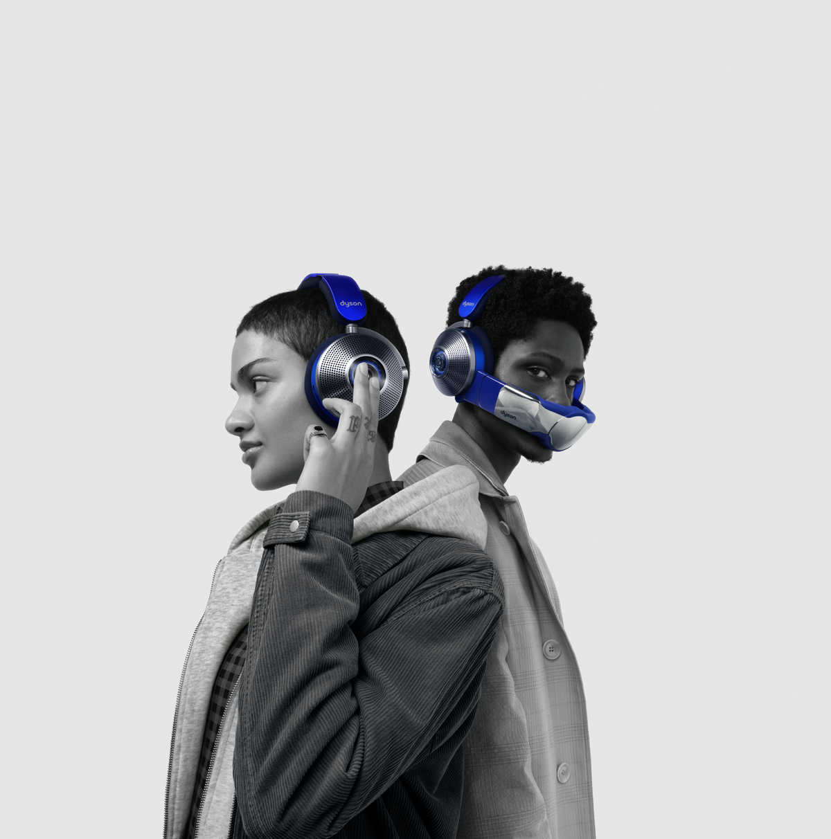 Dwie osoby w niebieskich słuchawkach tyłem do siebie. Jedna ich dotyka. Szare tło.