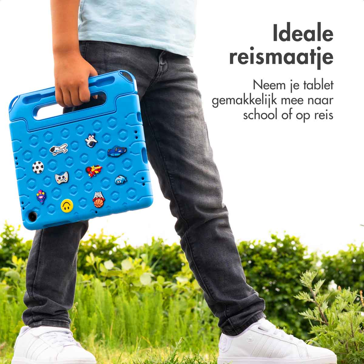 Boy holding a blue tablet case with stickers and handle. Jeans and white shoes are visible.