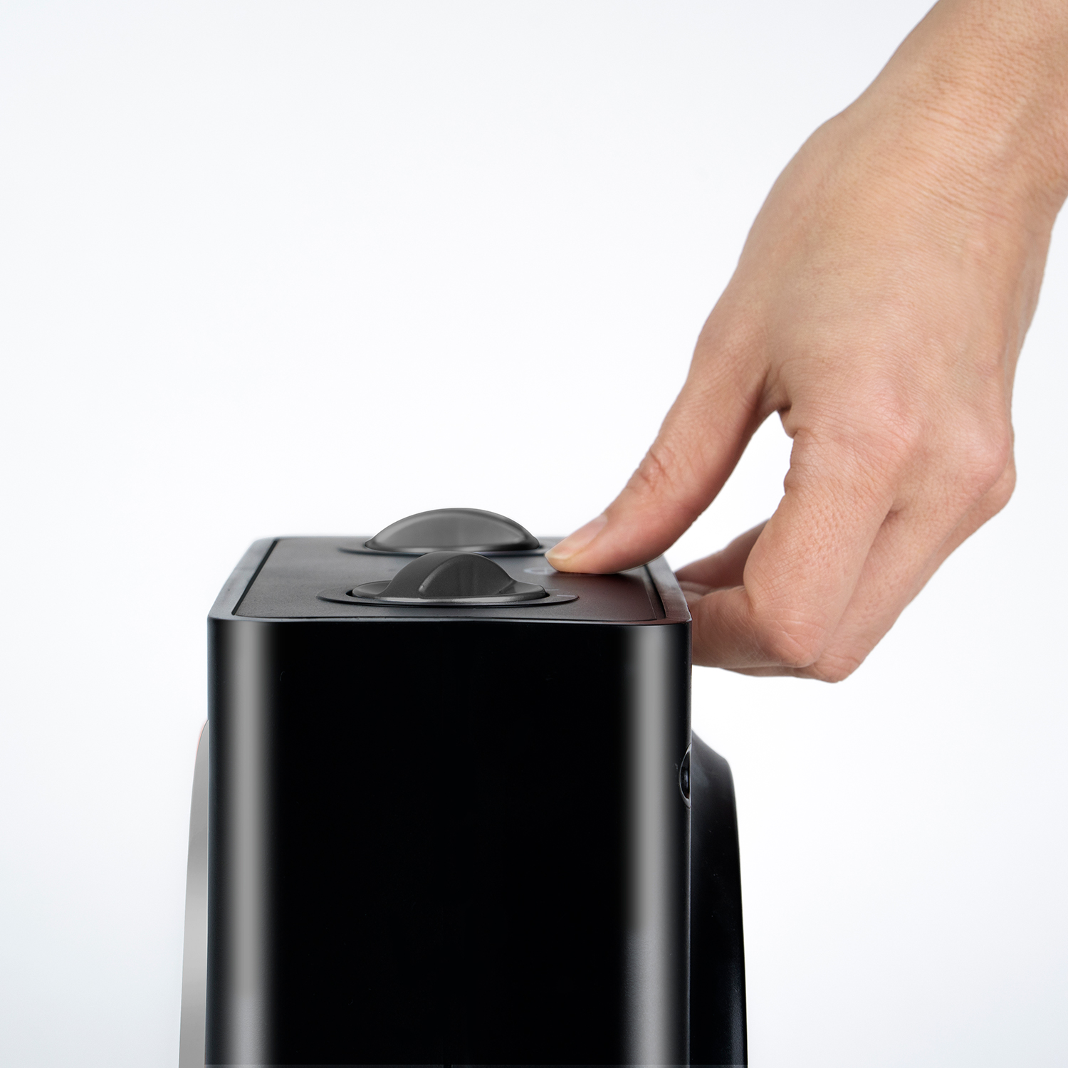 Ręka naciskająca przyciski na czarnym grzejniku. Białe tło.