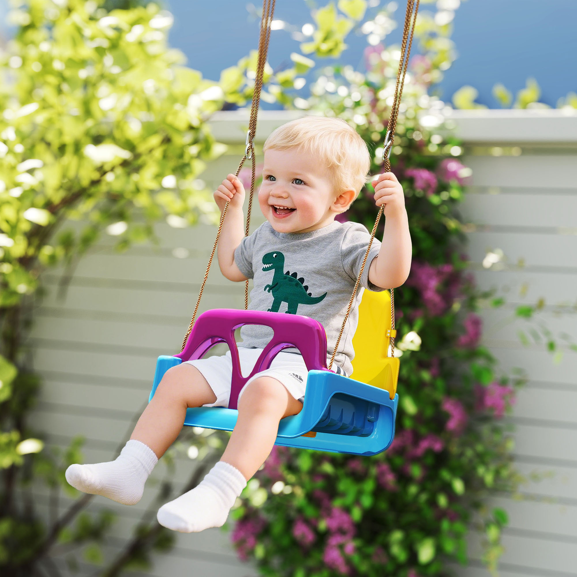 Un bambino piccolo sorride su un'altalena colorata in giardino.