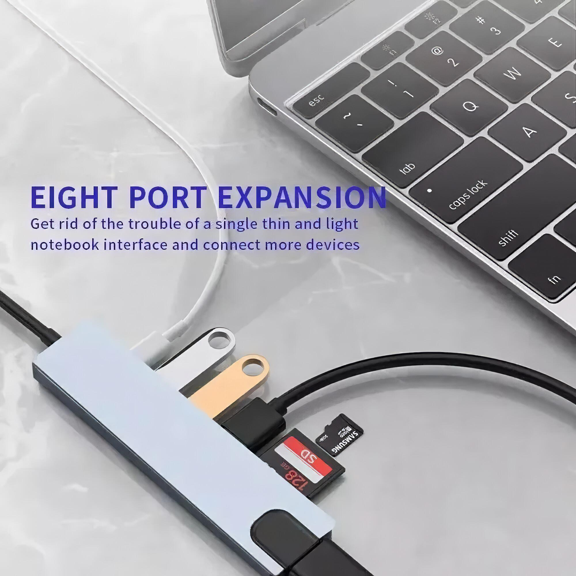 Ein Hub mit mehreren Anschlüssen und angeschlossenen Geräten, neben einer Laptop-Tastatur mit USB-Stick.