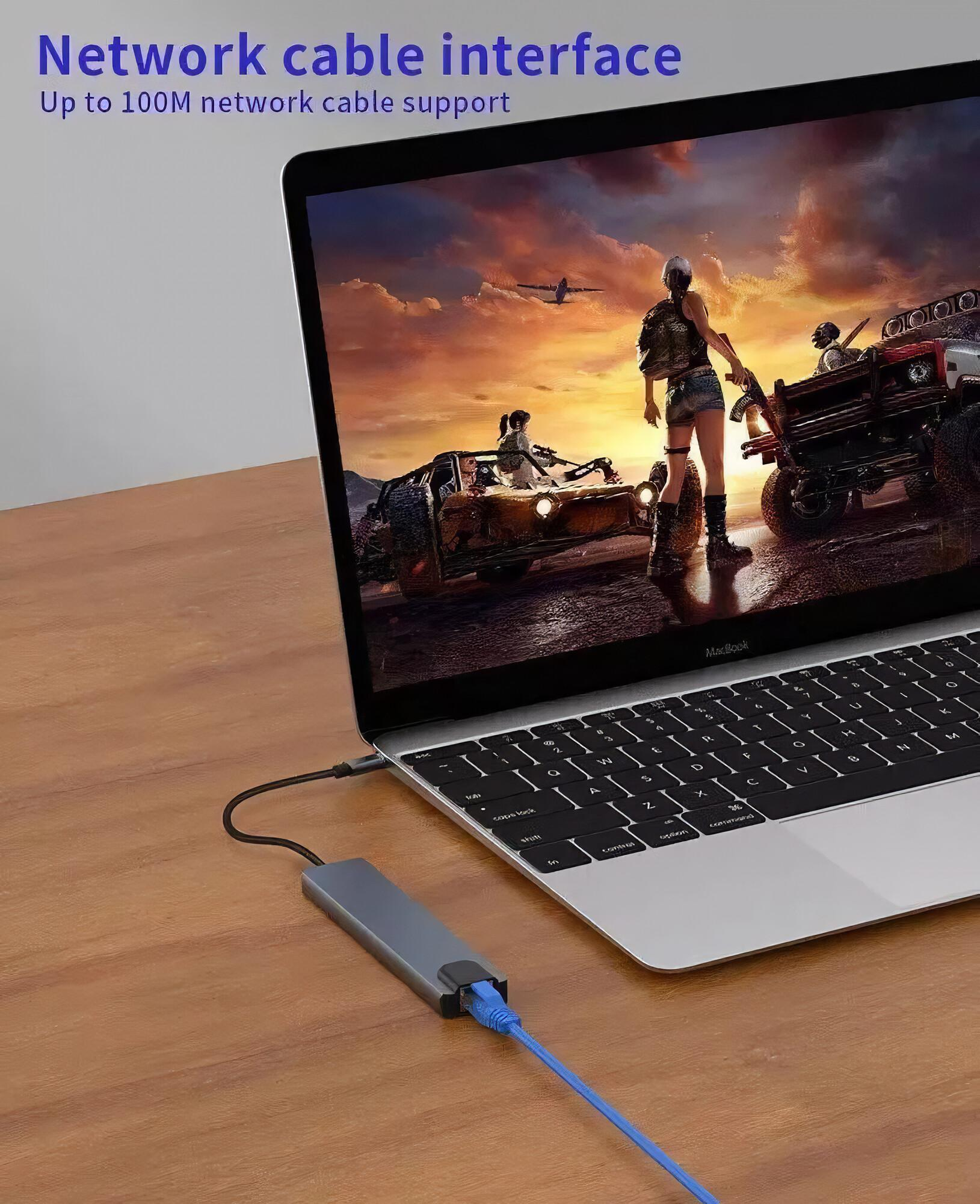 Laptop, der mit einem grauen Hub mit blauem Netzwerkkabel verbunden ist. Auf dem Laptop wird eine Spielszene angezeigt.
