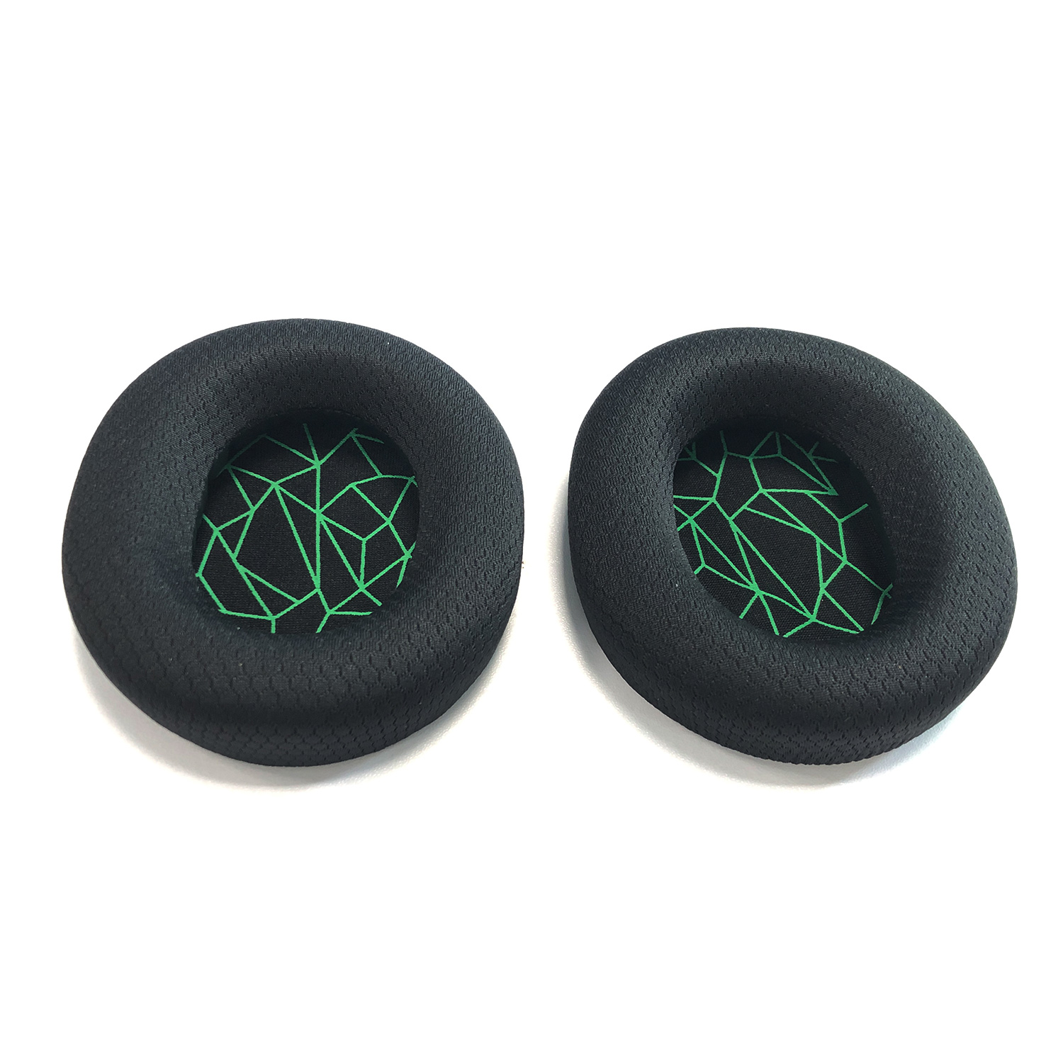 Dwie czarne nauszniki z zielonymi geometrycznymi wzorami wewnątrz, na białym tle.