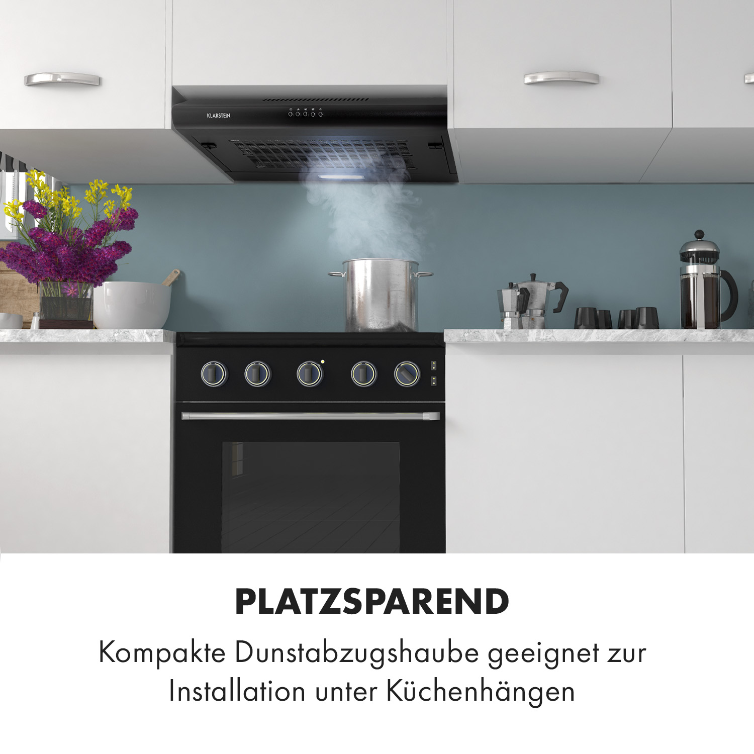 Cocina con campana extractora y estufa. Texto: 'PLATZSPAREND' e instalación bajo armarios.