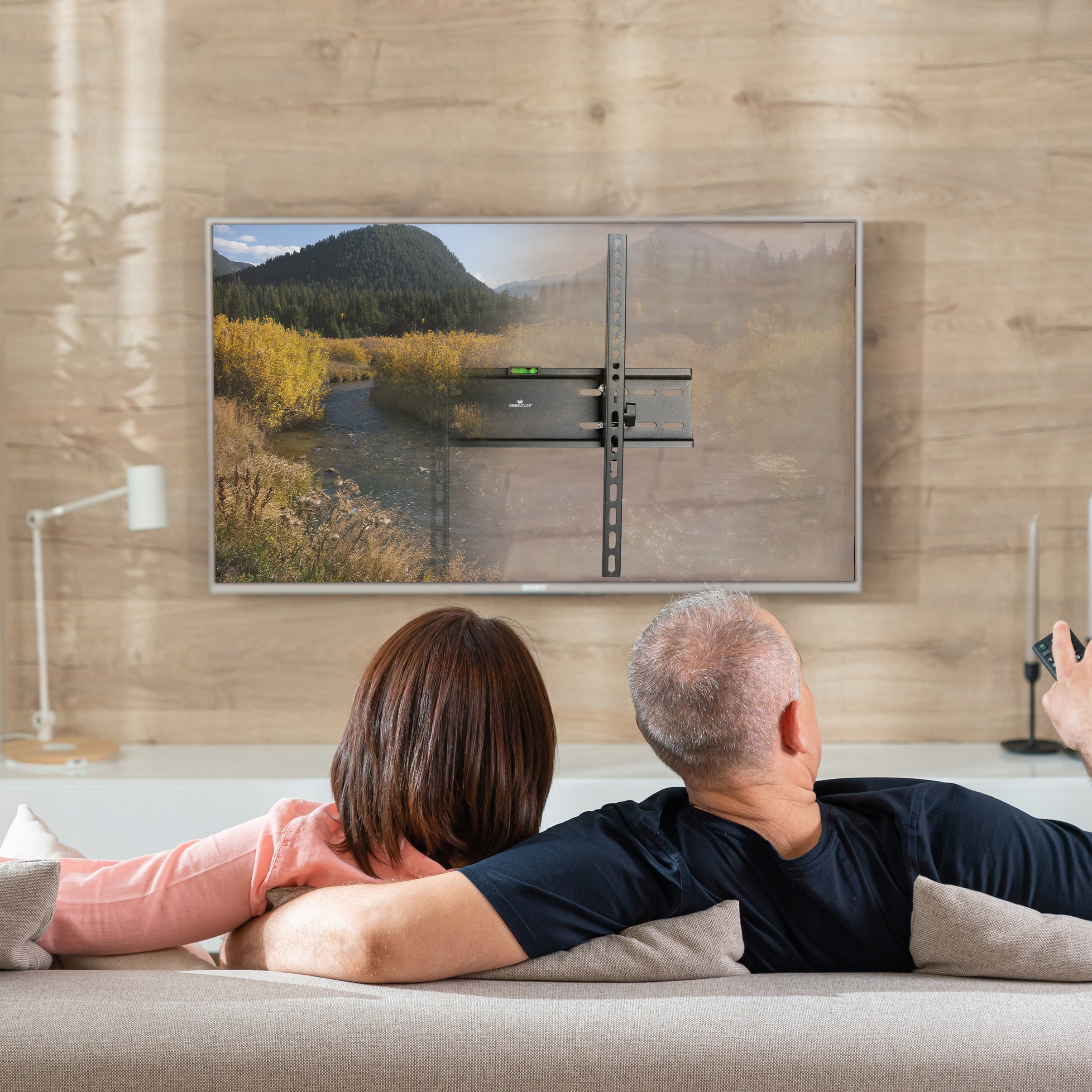 Para na kanapie oglądająca telewizję zamontowaną na uchwycie TV.