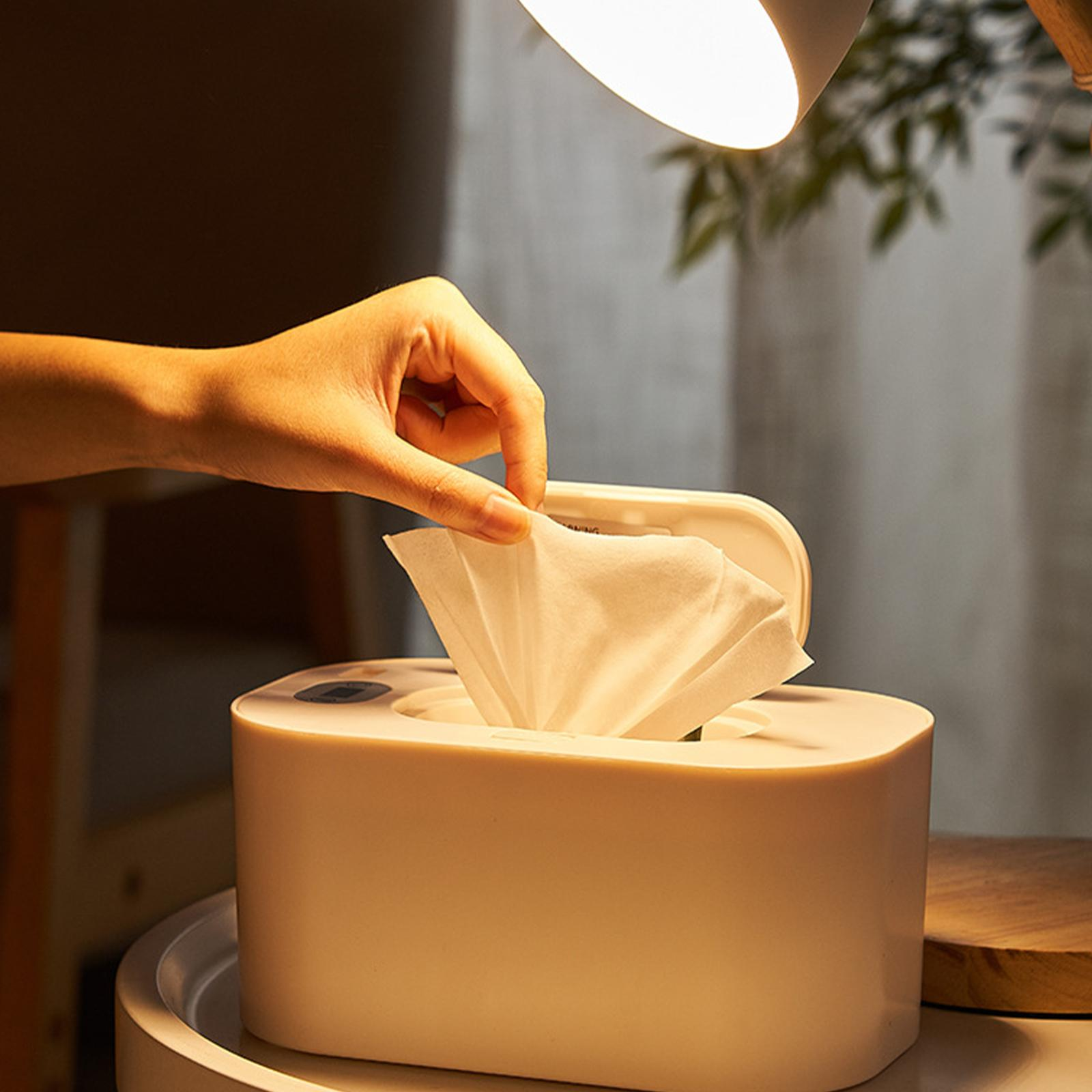 Hand zieht ein Taschentuch aus einem weißen Spender. Eine Lampe ist darüber.
