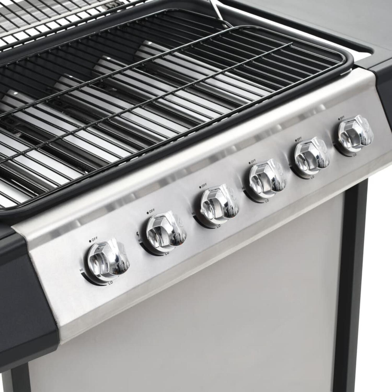 Nahaufnahme eines Edelstahlgrills mit Bedienelementen und einem Kochrost.