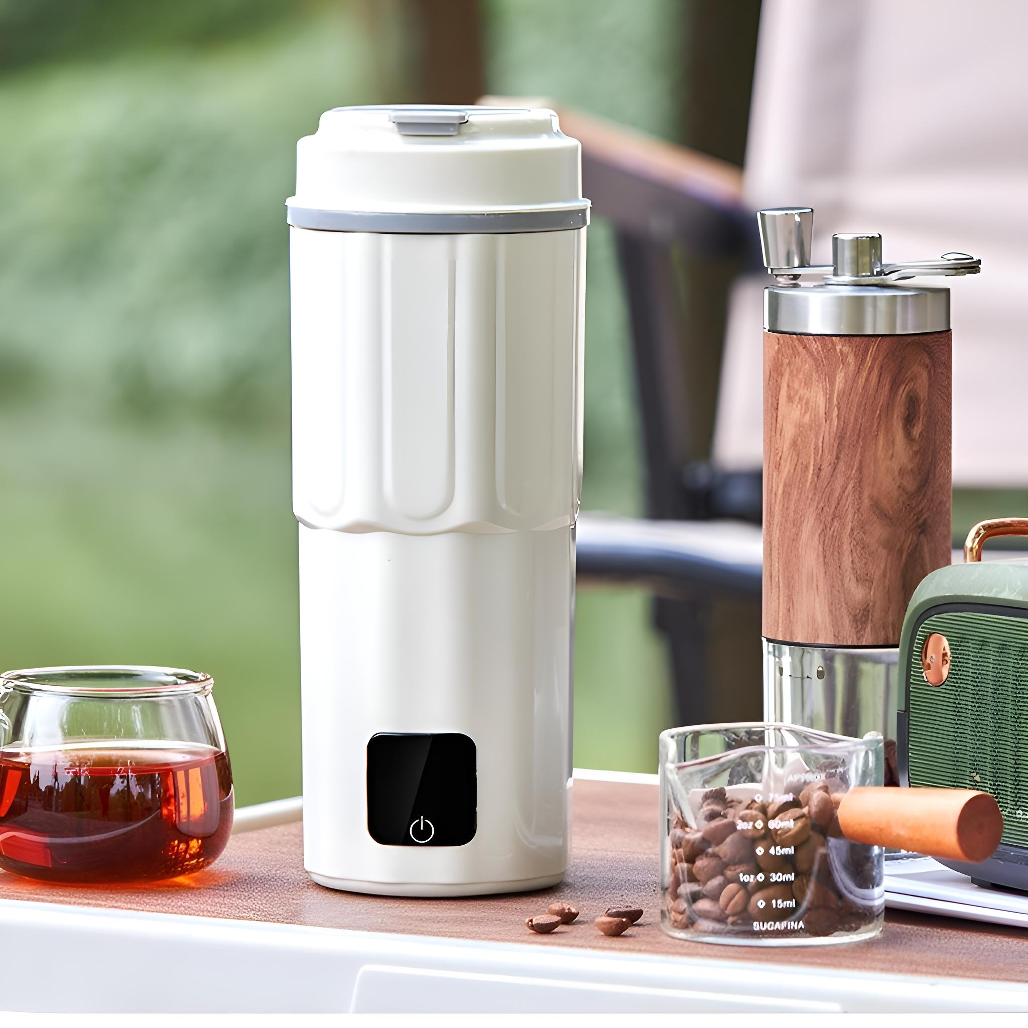 Weißer, tragbarer Kaffeebereiter mit Holzmahlwerk und Glasmessbecher mit Kaffeebohnen.