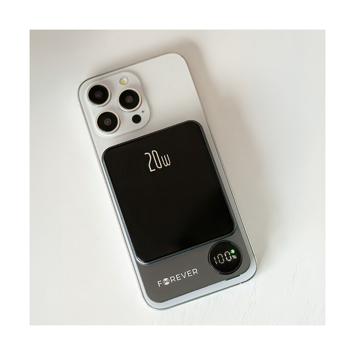 Silbernes iPhone mit angebrachter schwarzer Powerbank. Die Powerbank zeigt 20W und 100% Ladung an.