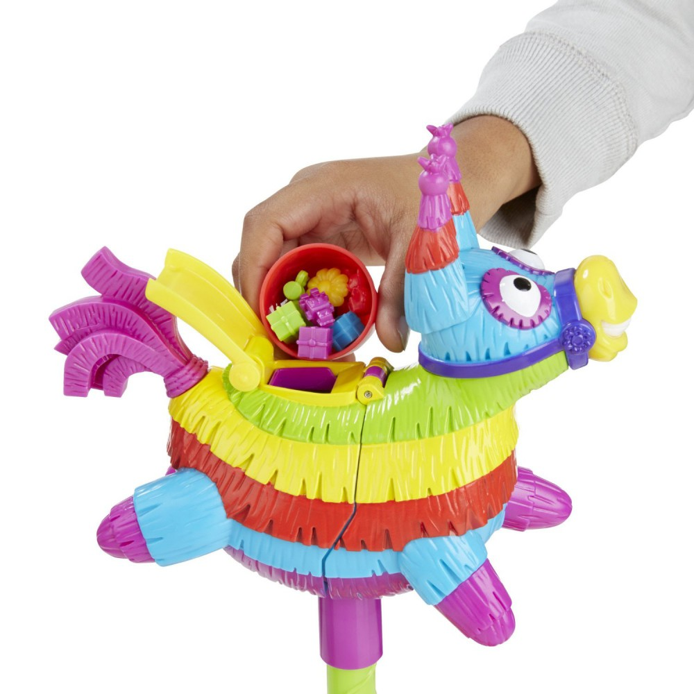 Ein mehrfarbiges Pinata-Spielzeug in Form eines Esels. Eine Hand hält eine Schüssel, um Süßigkeiten aufzufangen.