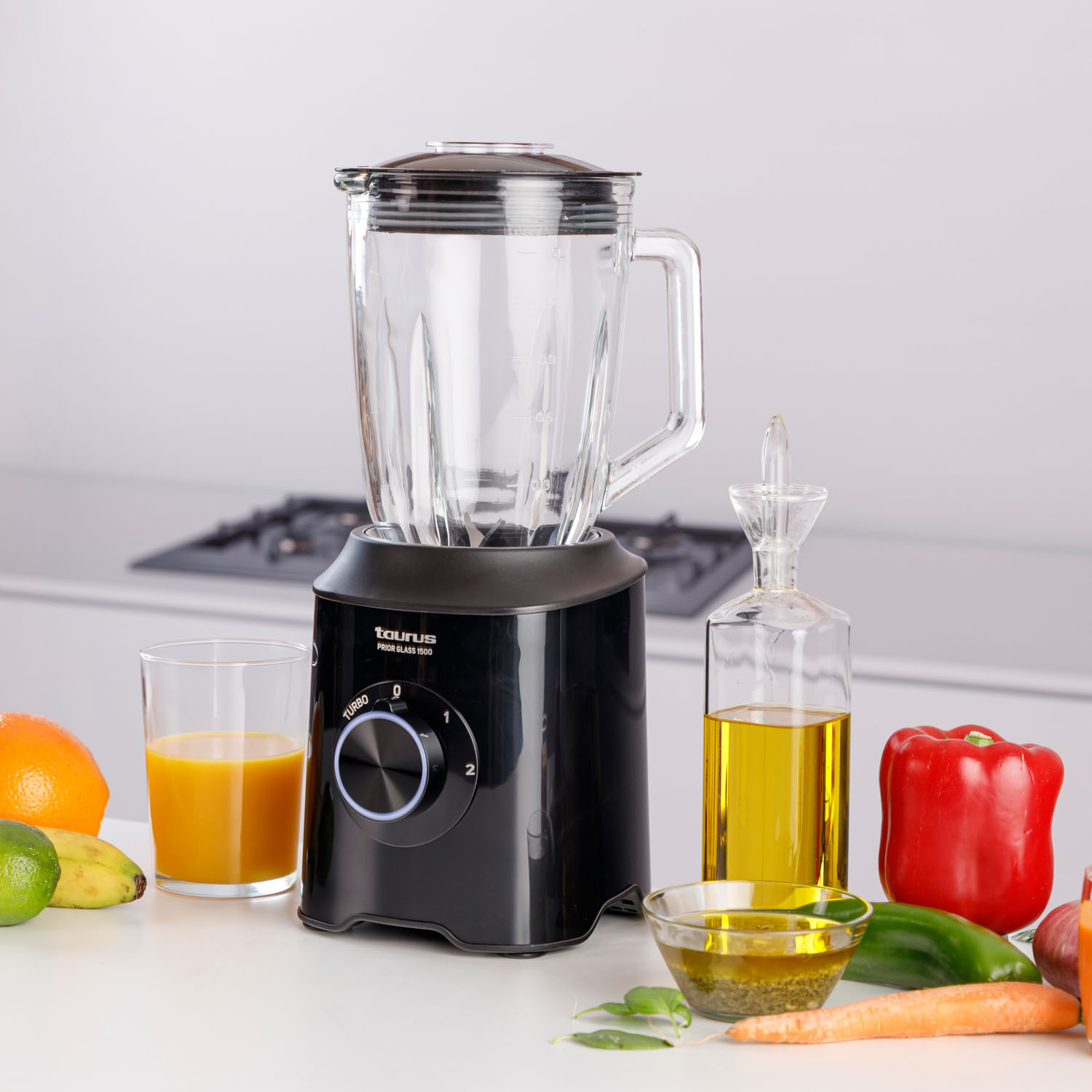 Czarny blender z owocami, warzywami i olejem na stole.