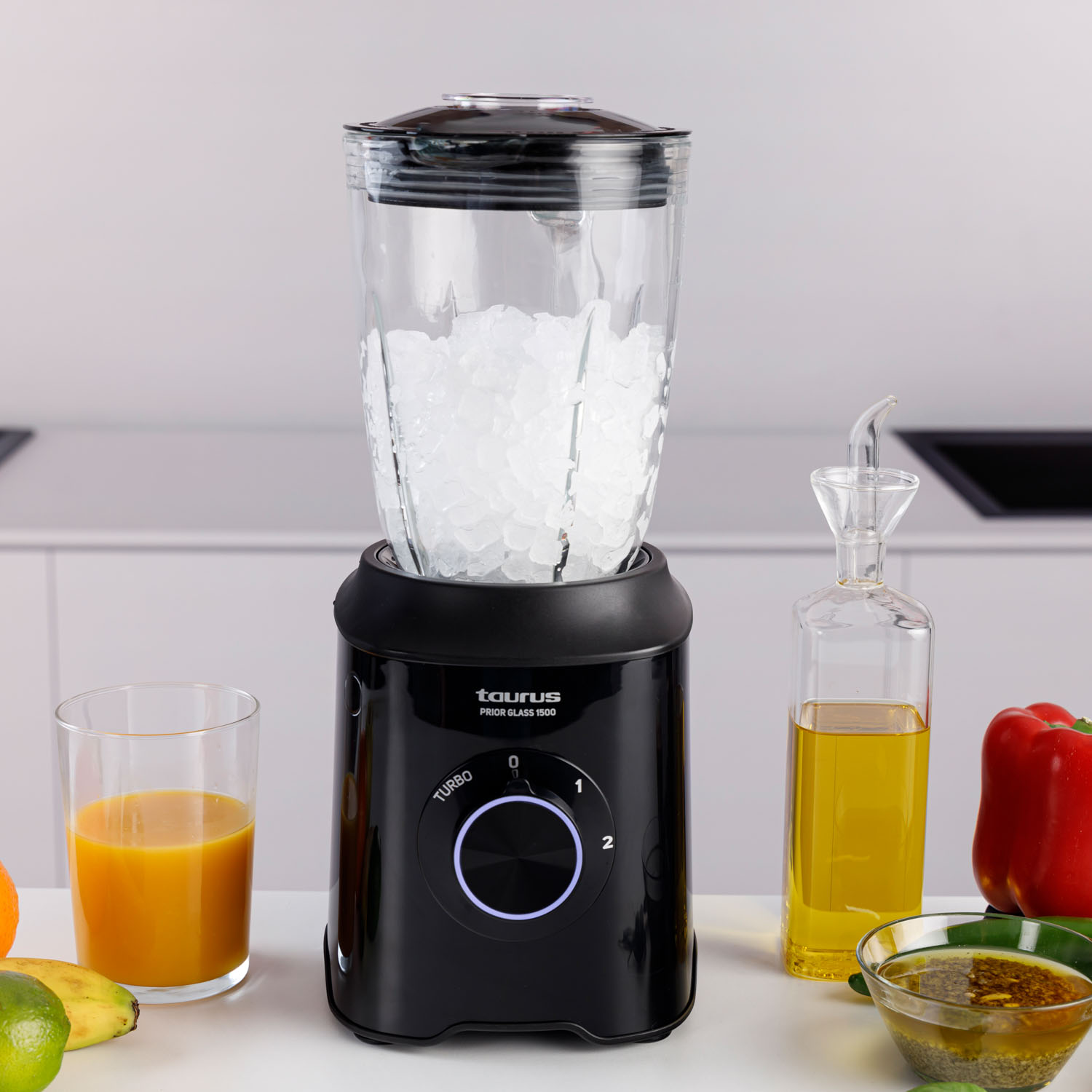 Blender z lodem w środku. Inne składniki i szklanka na blacie.