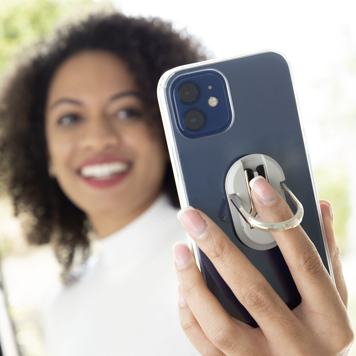 Donna che tiene in mano un telefono con un porta anelli, sorridente.