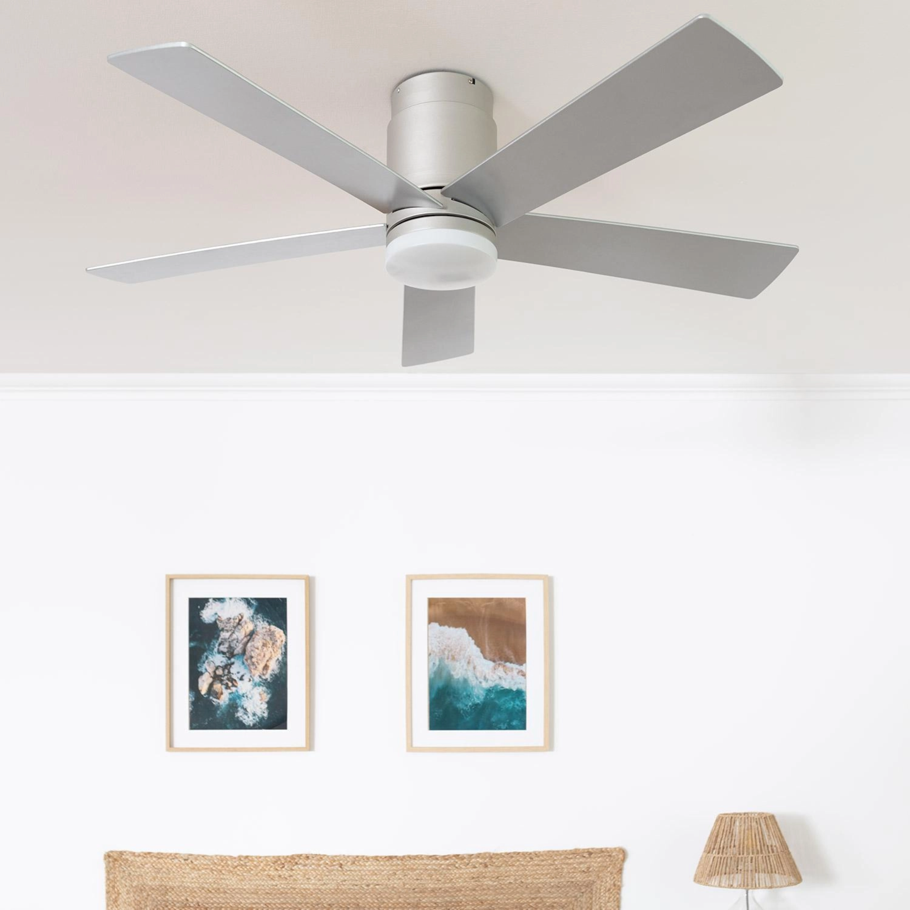 Camera da letto con ventilatore da soffitto, letto, arte, lampada. Muri e soffitto bianchi.