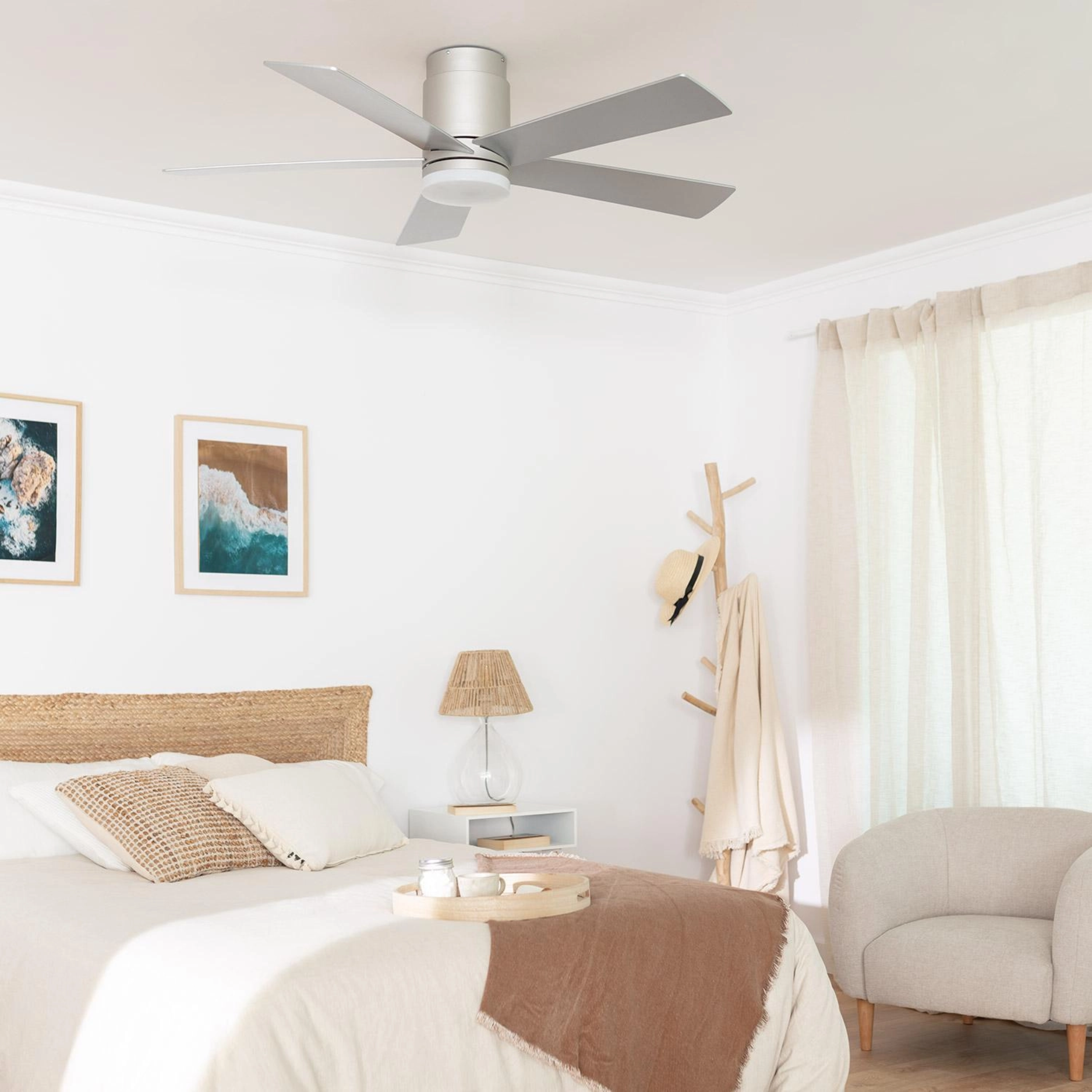 Scena della camera da letto con un ventilatore da soffitto. Letto, arte, lampada e poltrona visibili.