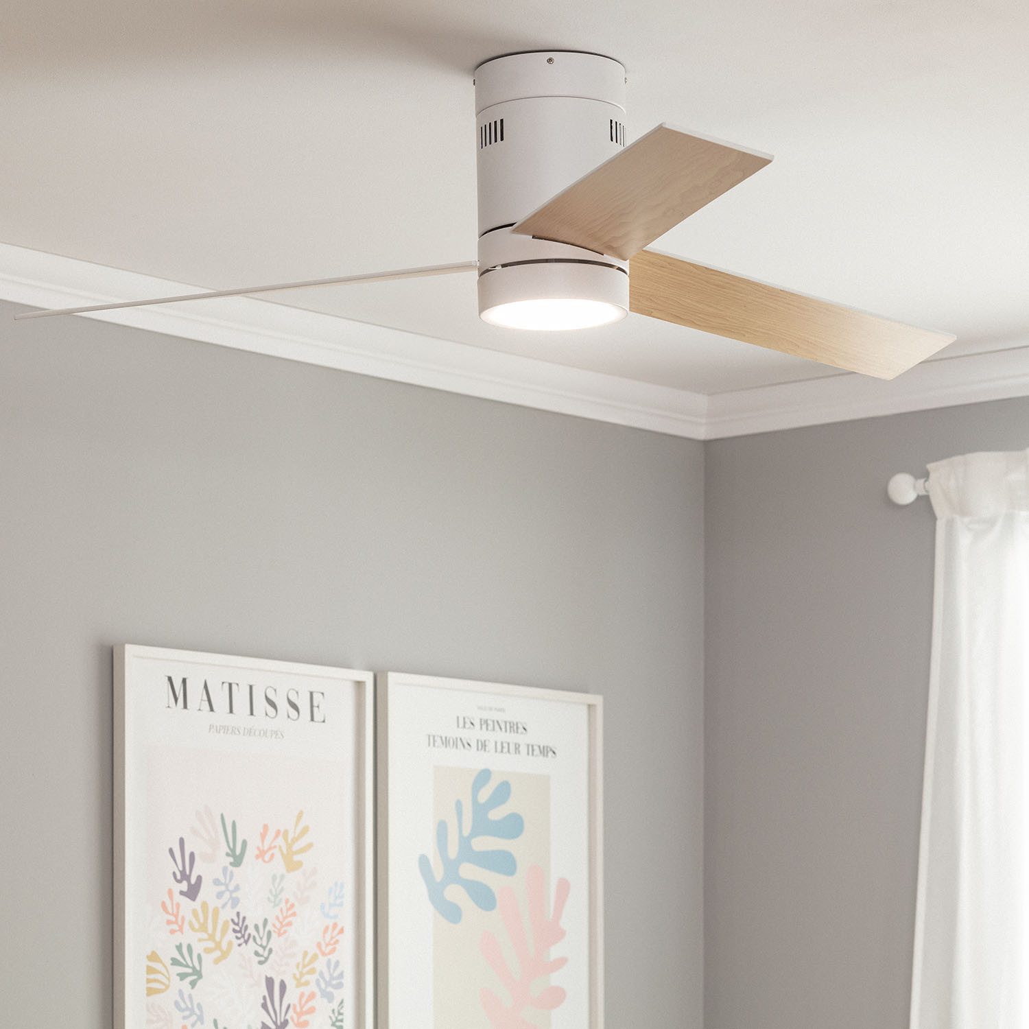 Ventilatore da soffitto con pale in legno, luce e due opere d'arte incorniciate. Muri grigi.