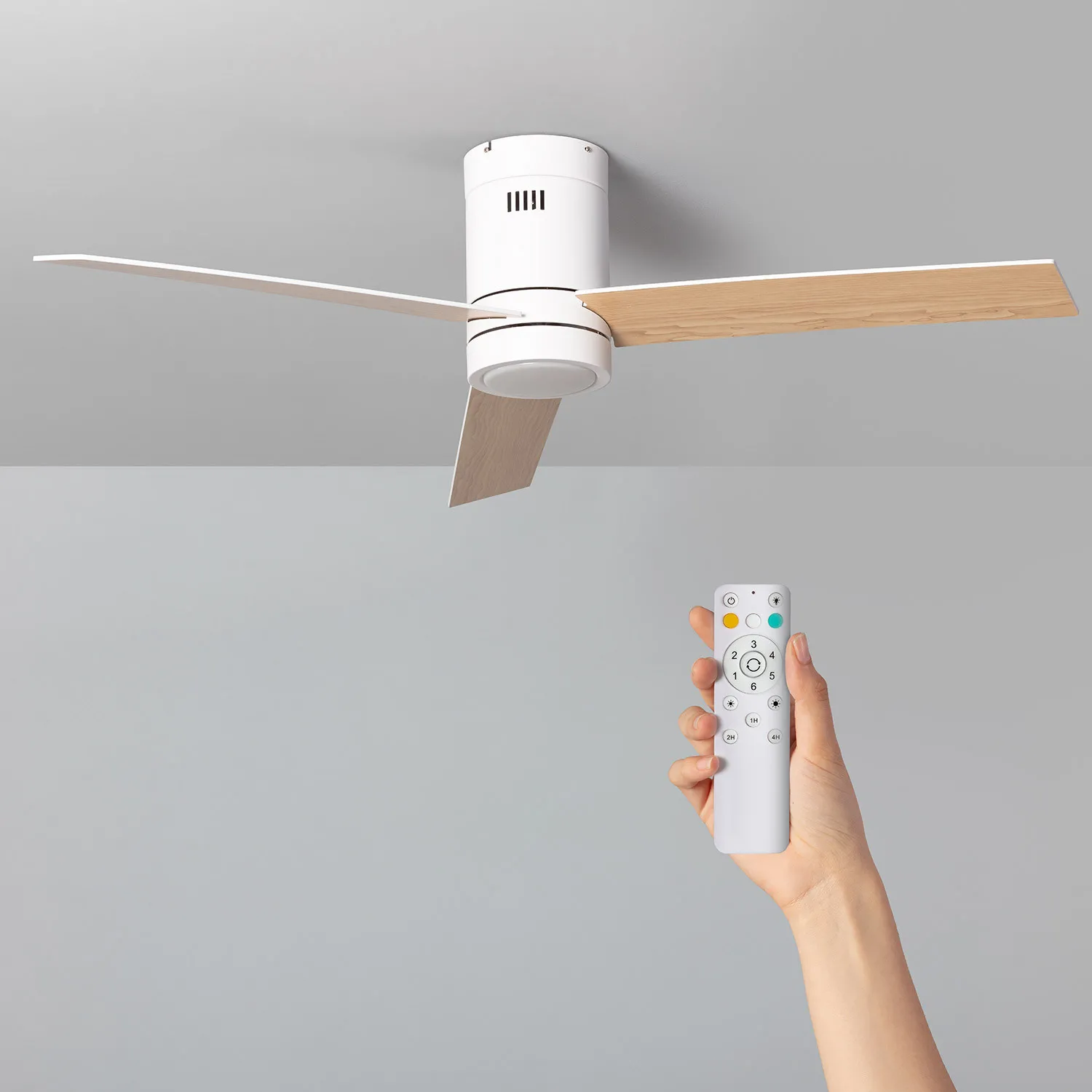 Ventilatore da soffitto bianco con due pale e telecomando. Il telecomando è in una mano. Lo sfondo è grigio.