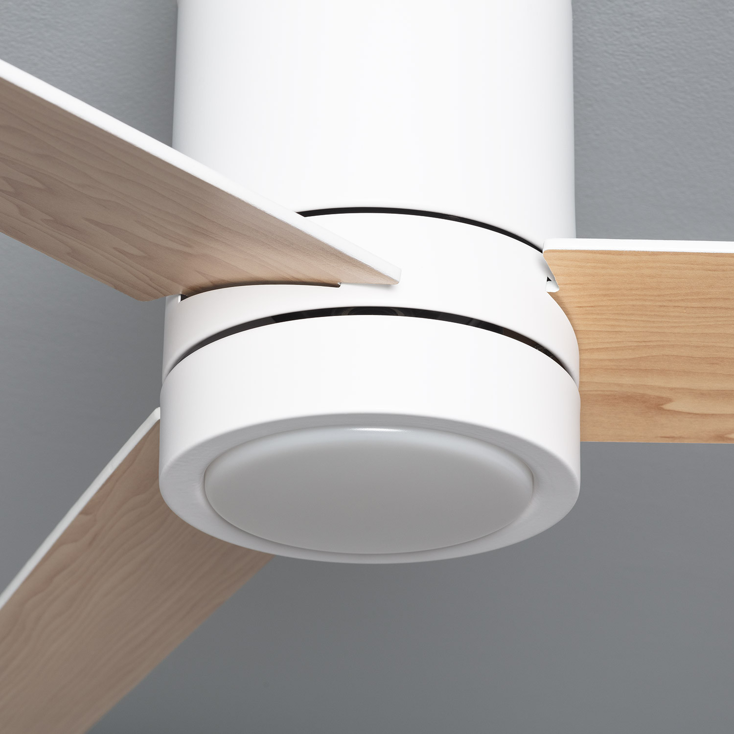 Primo piano del ventilatore da soffitto con pale in legno e una luce. Lo sfondo è grigio.