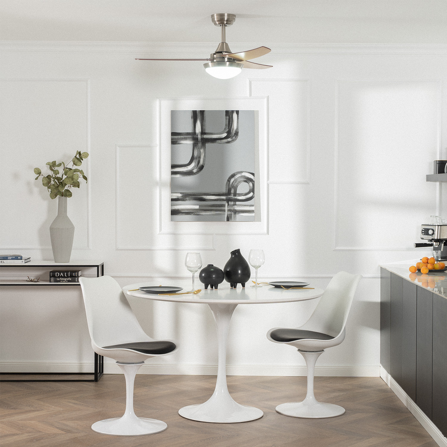 Sala da pranzo con tavolo rotondo, due sedie bianche e ventilatore a soffitto.