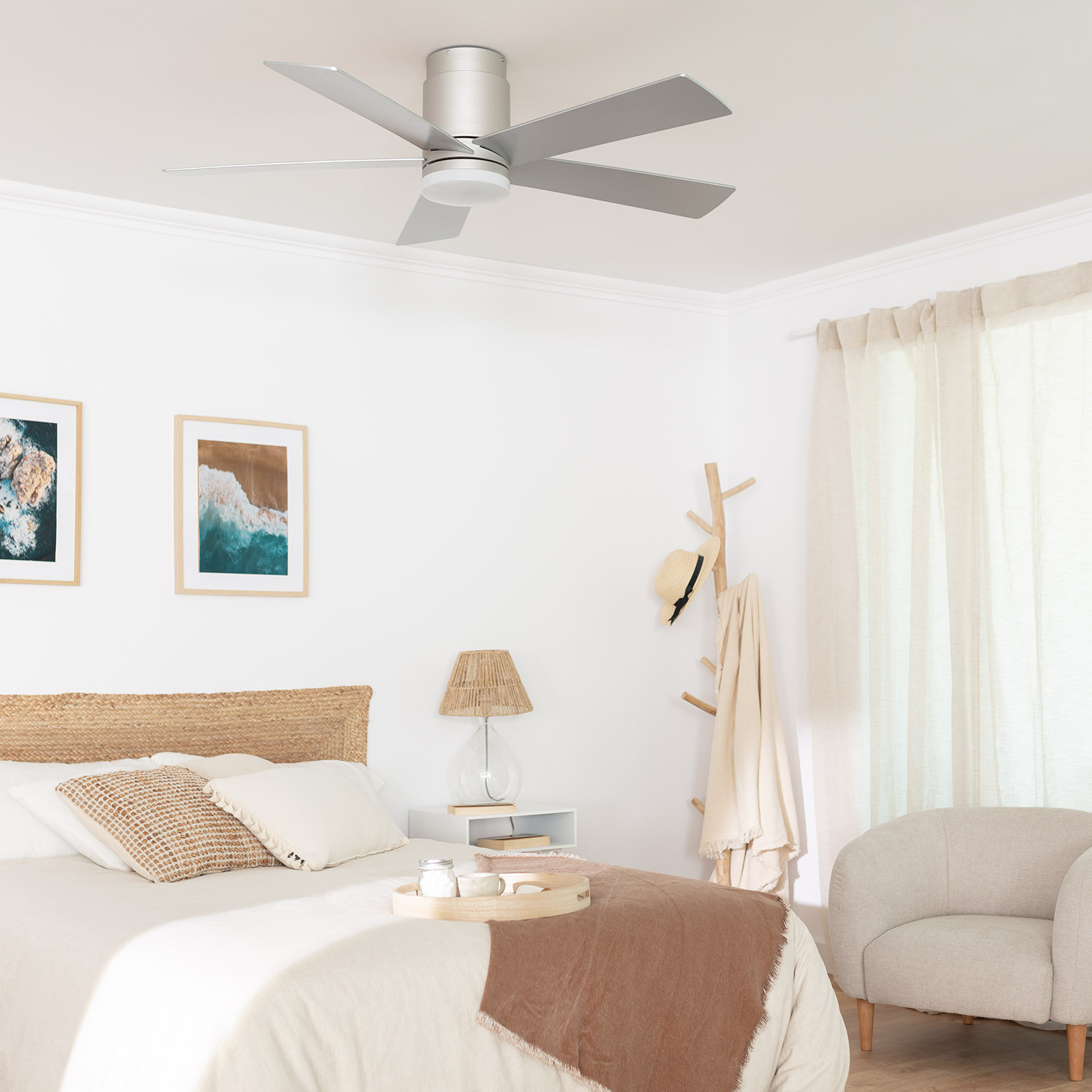 Camera da letto con ventilatore a soffitto, arte, letto e schema di colori neutri.