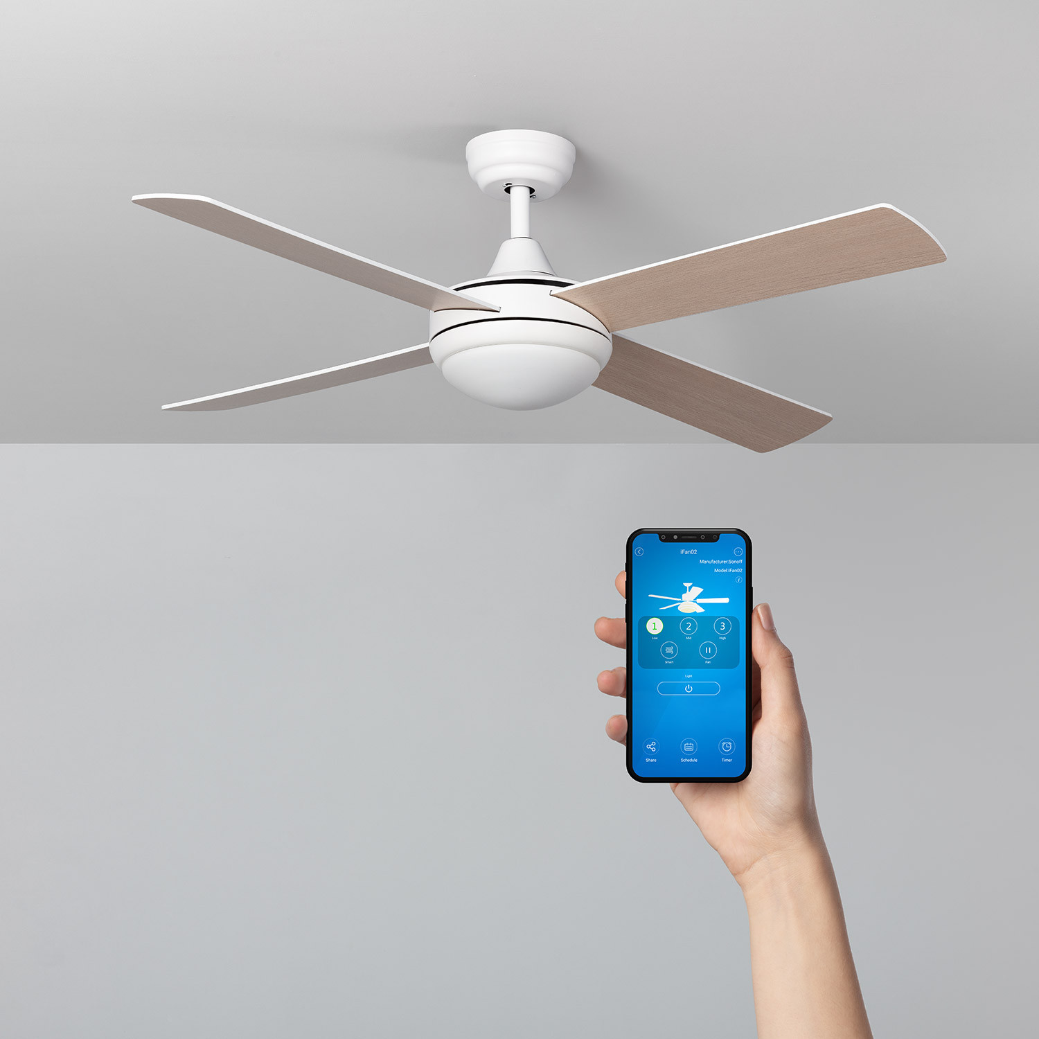 Ventilatore a soffitto bianco con pale in legno. Mano che tiene telefono con app.