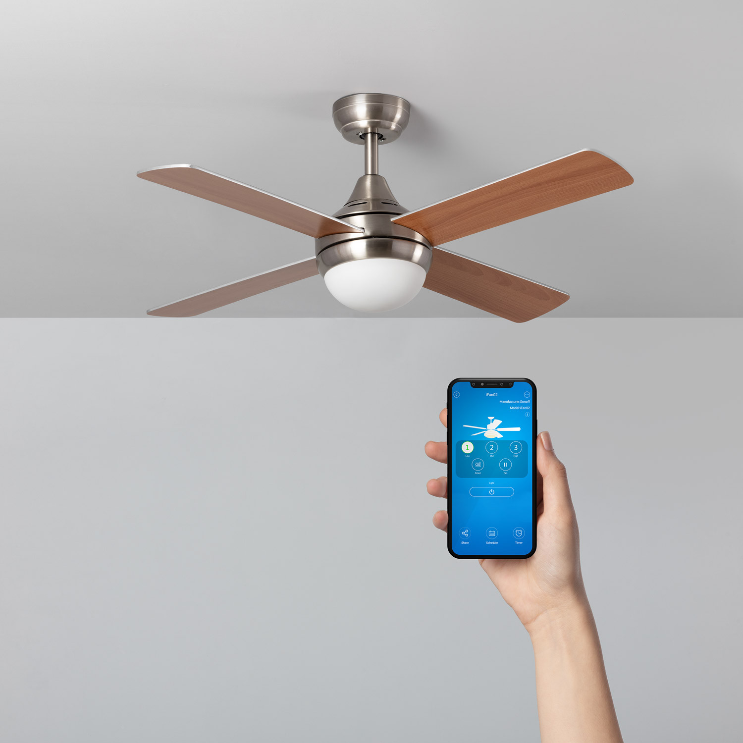Ventilatore da soffitto con quattro pale marroni. Una mano che tiene un telefono con opzioni di controllo del ventilatore.