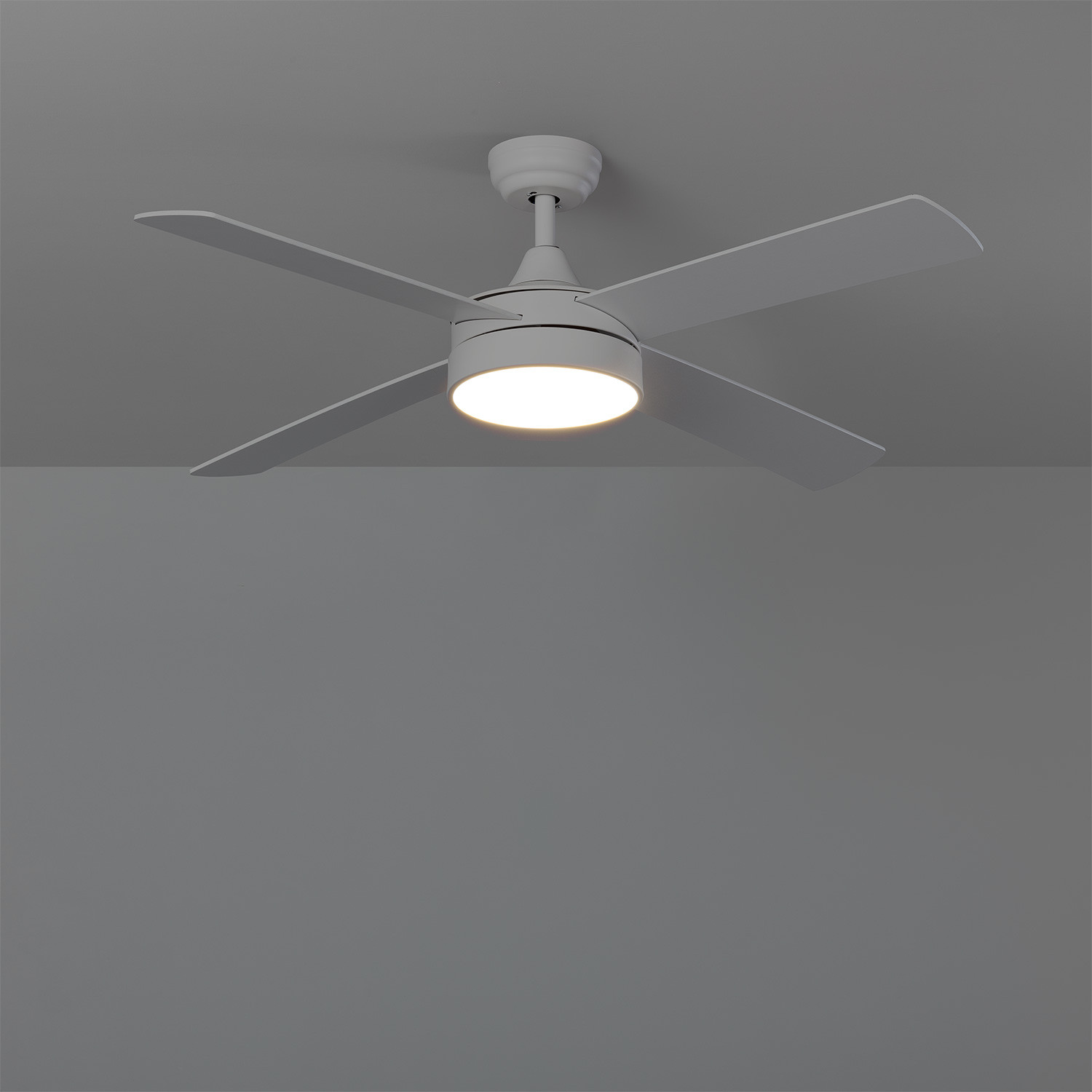 Un ventilatore da soffitto bianco con quattro pale e un apparecchio di illuminazione centrale in un soffitto grigio.