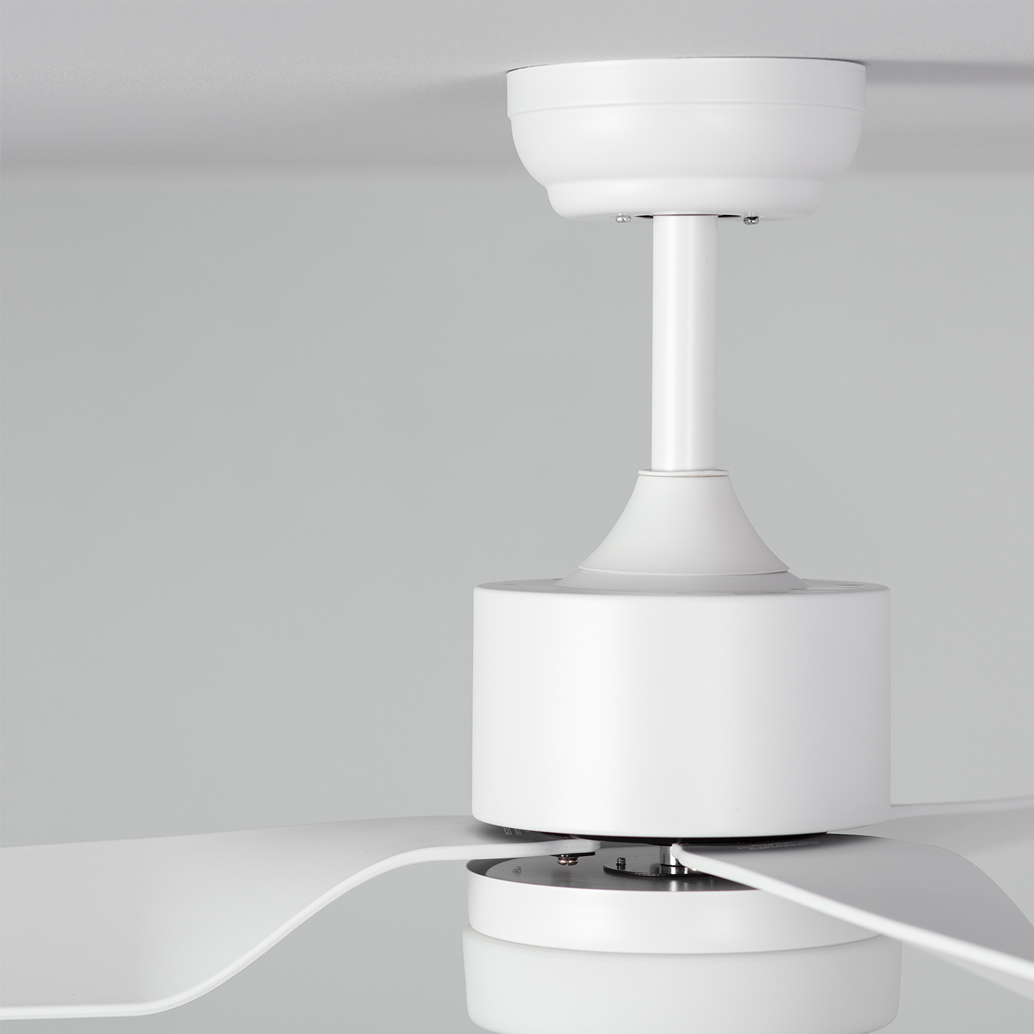 Primo piano di ventilatore a soffitto bianco. Soffitto e pale bianche. Nessun altro dettaglio.