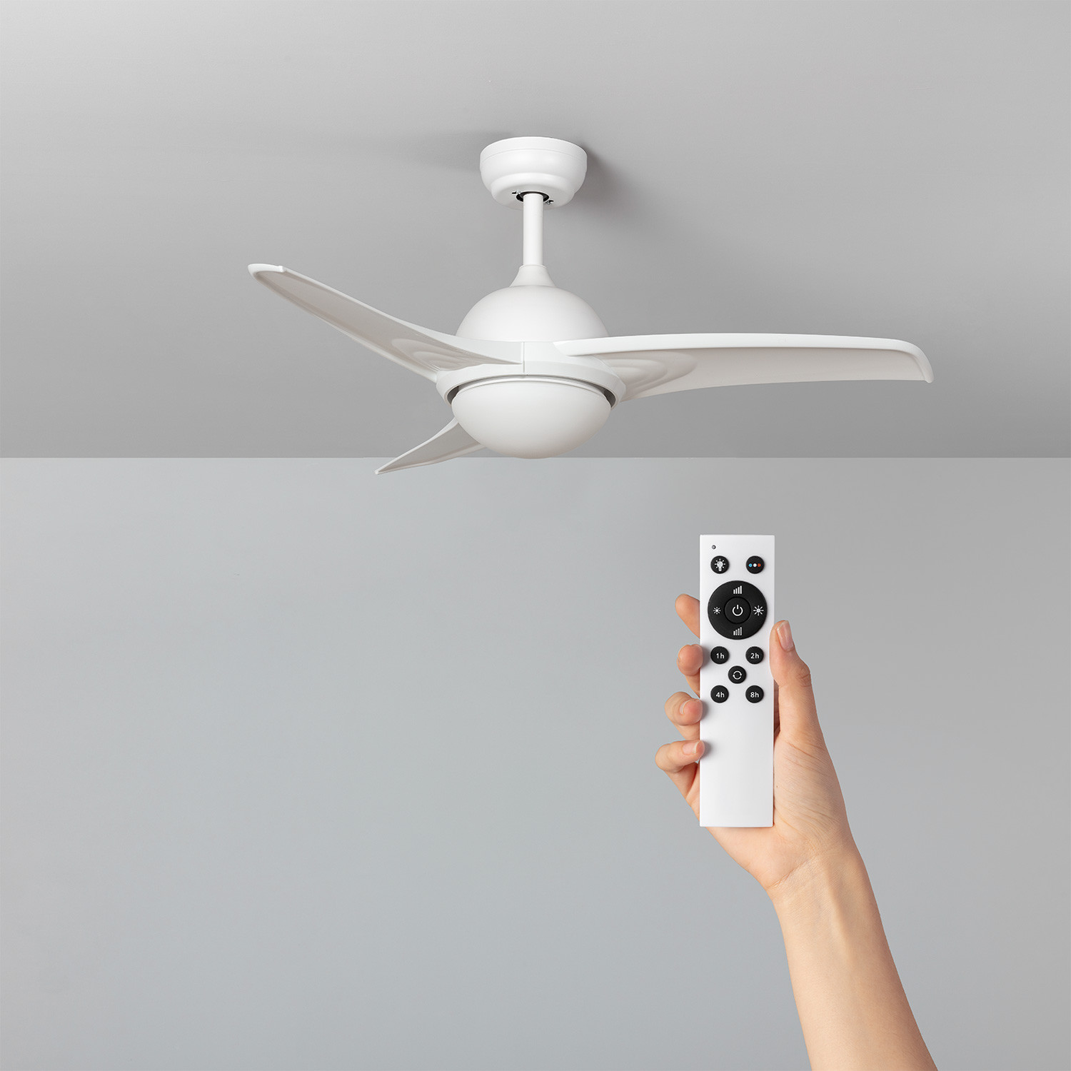 Ventilatore da soffitto bianco a tre pale, controllato da una mano con telecomando.