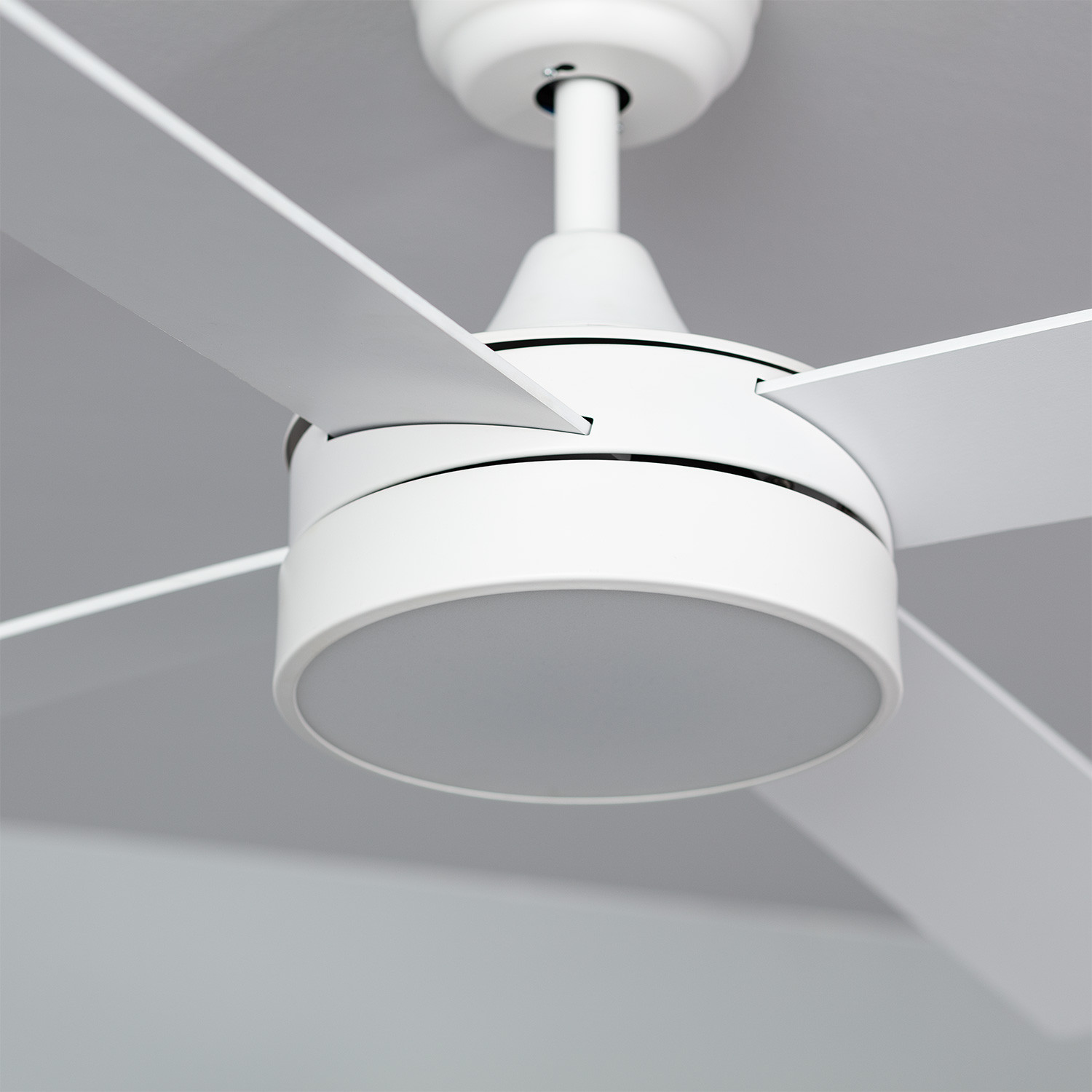 Un ventilatore da soffitto bianco con quattro pale e un apparecchio di illuminazione centrale, vista ravvicinata dal basso.